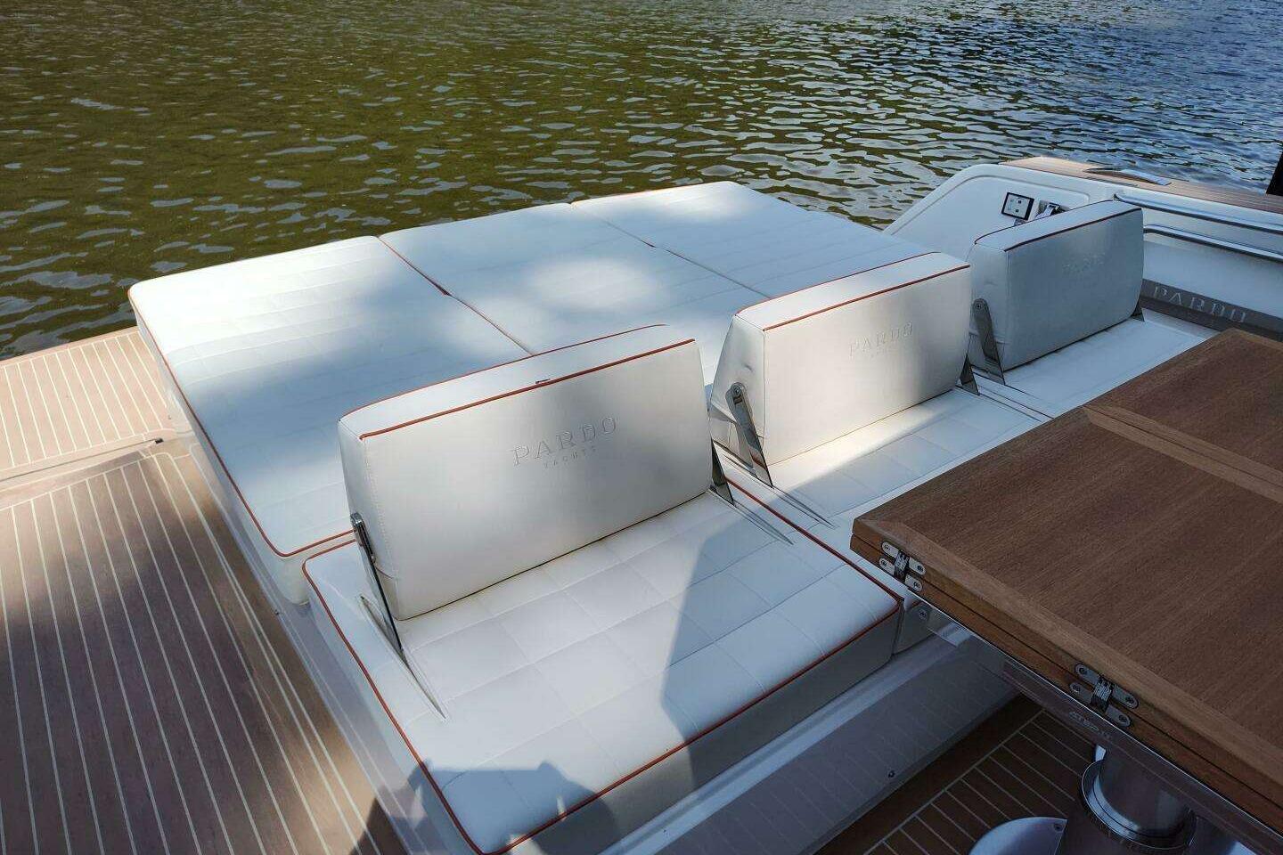 Luxury seating area on 2023 Pardo Yachts P43, featuring elegant white cushions and wooden table.