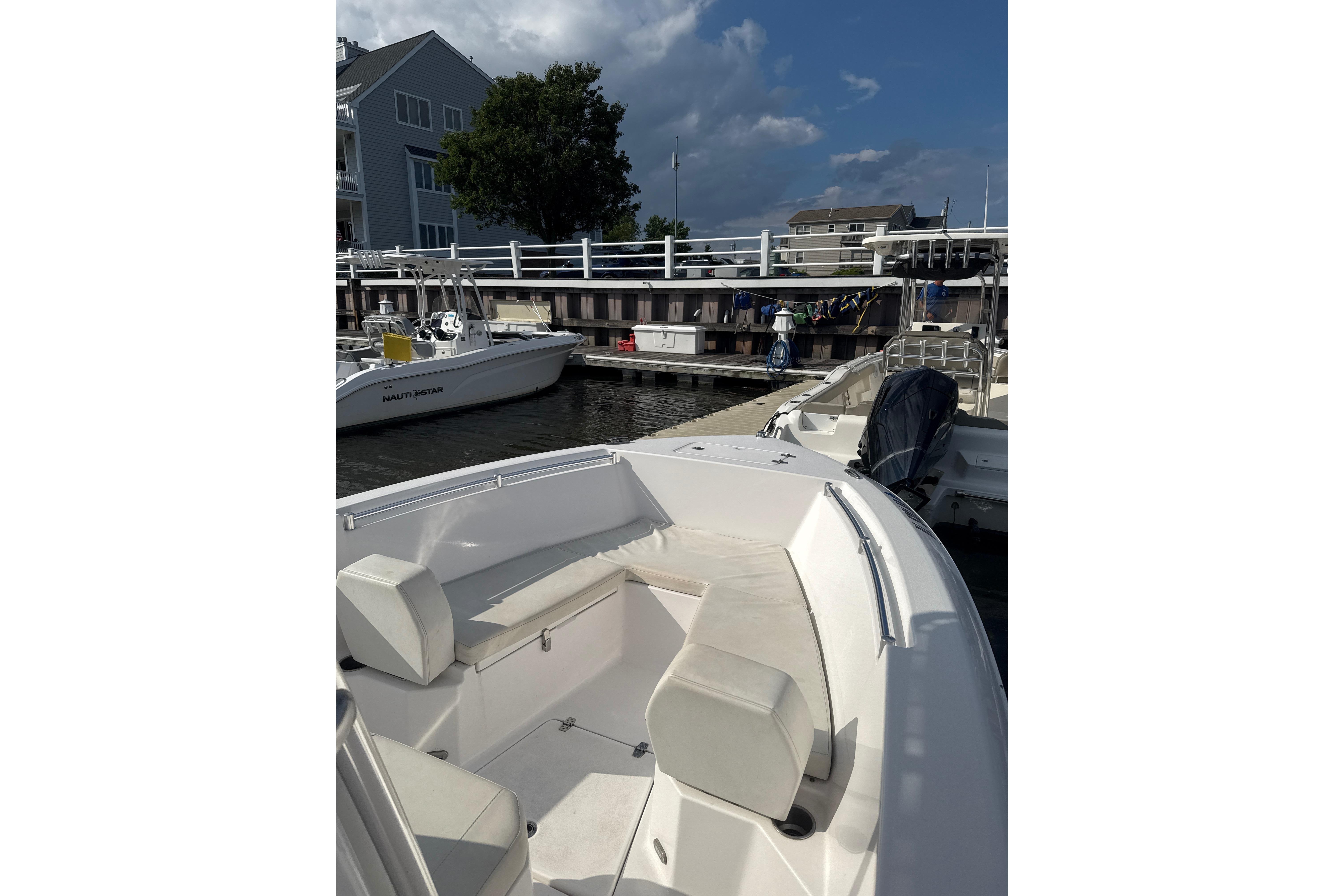 2024 Aquasport 2200 Center Console boat docked at marina under cloudy sky.