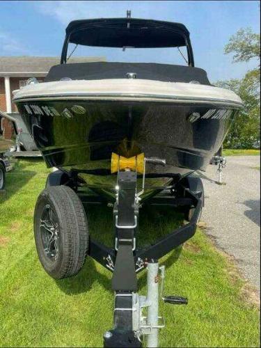 2022 Chaparral 23 Surf boat on trailer, parked on grass.