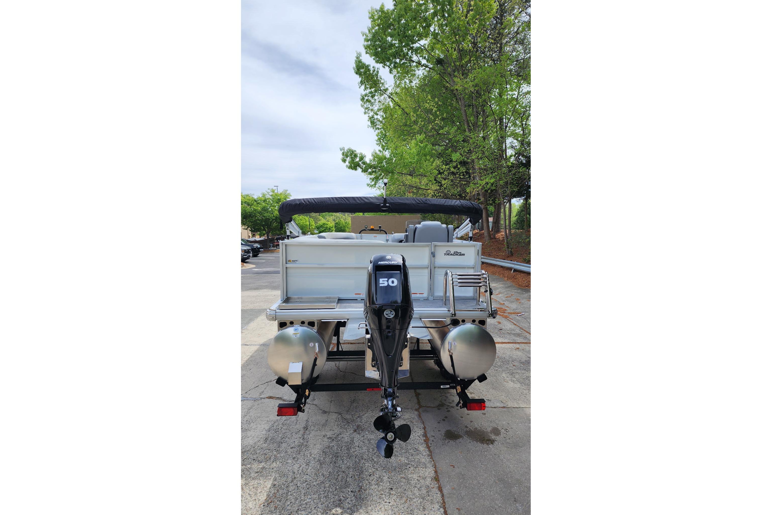 2026 Sun Tracker Party Barge 16 DLX pontoon boat with outboard motor, parked outdoors.