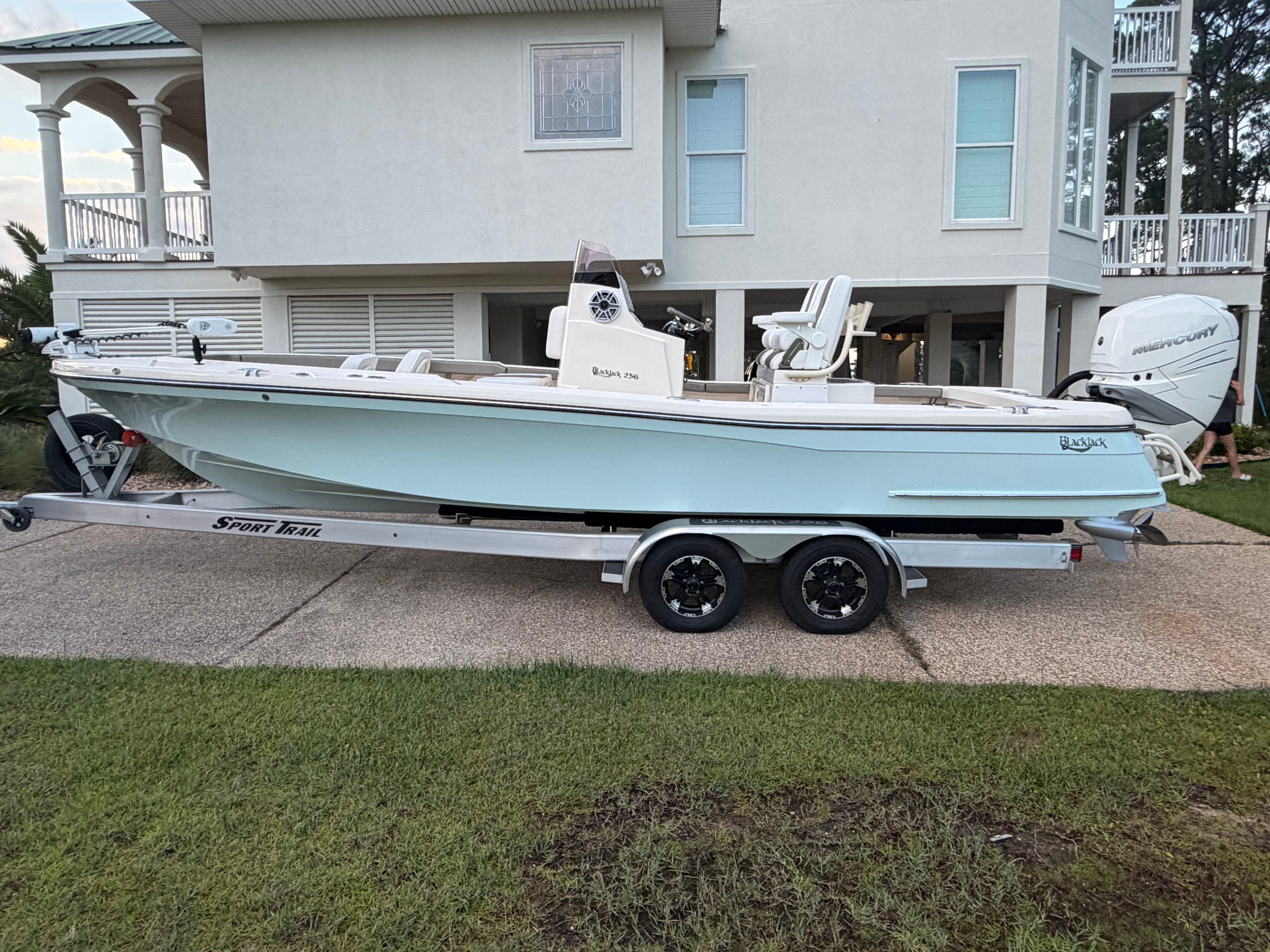 2022 BlackJack 256 Coastal boat on trailer in front of house.