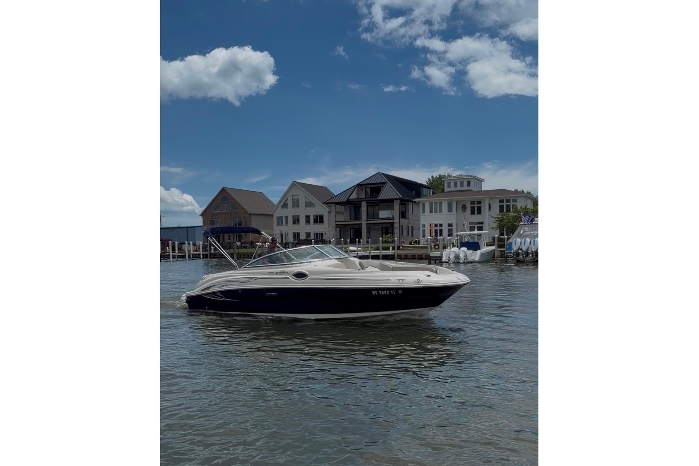 2004 Sea Ray 240 Sundeck boat on water, with waterfront homes in the background.