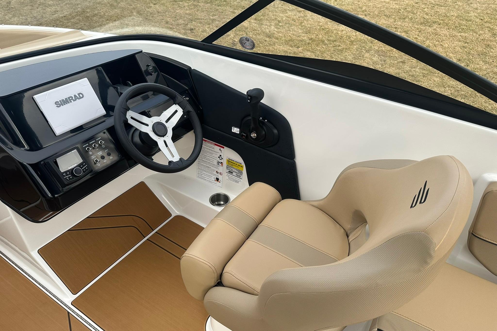 2026 Bayliner V20 boat cockpit with steering wheel, Simrad display, and beige seating.