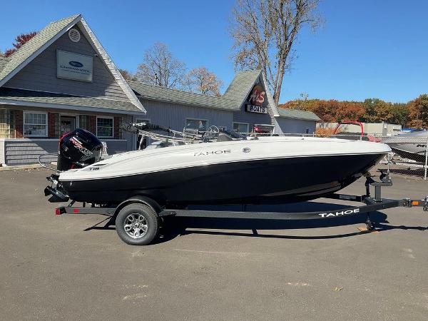 2025 Tahoe T18 boat on trailer, parked outside dealership on sunny day.