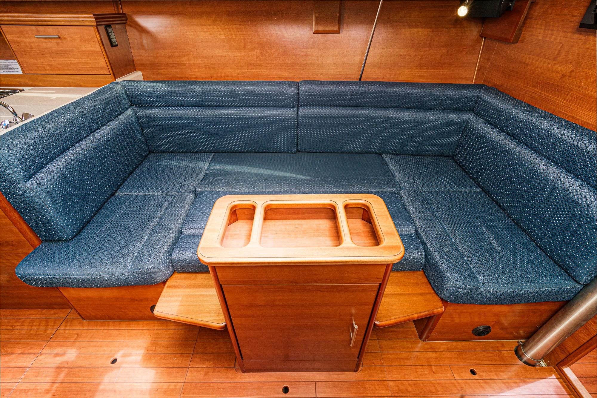 2015 Hunter 33 yacht interior with blue cushioned seating and wooden table.