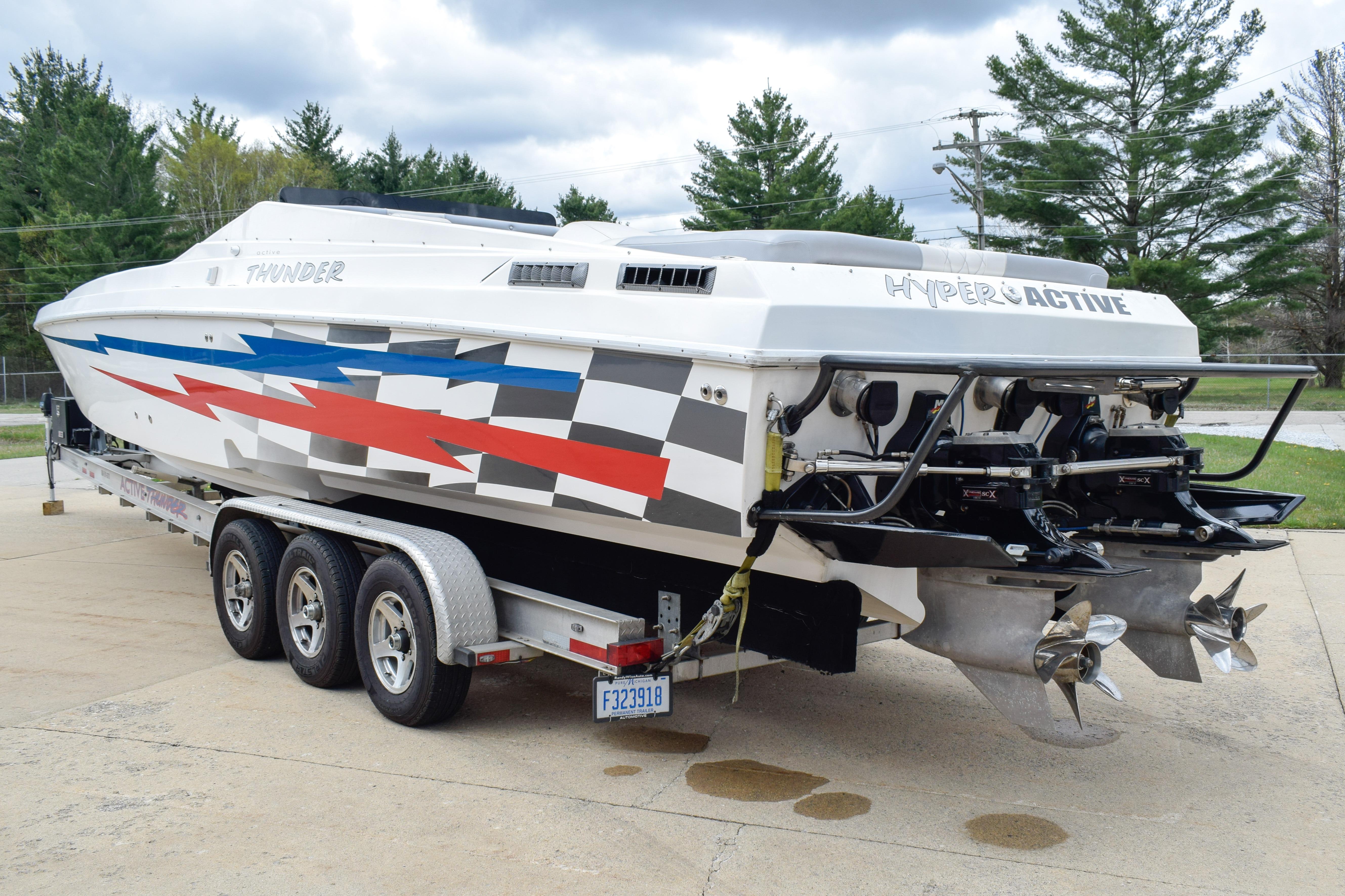 2002 Active Thunder 37 powerboat with vibrant graphics on a triple-axle trailer.
