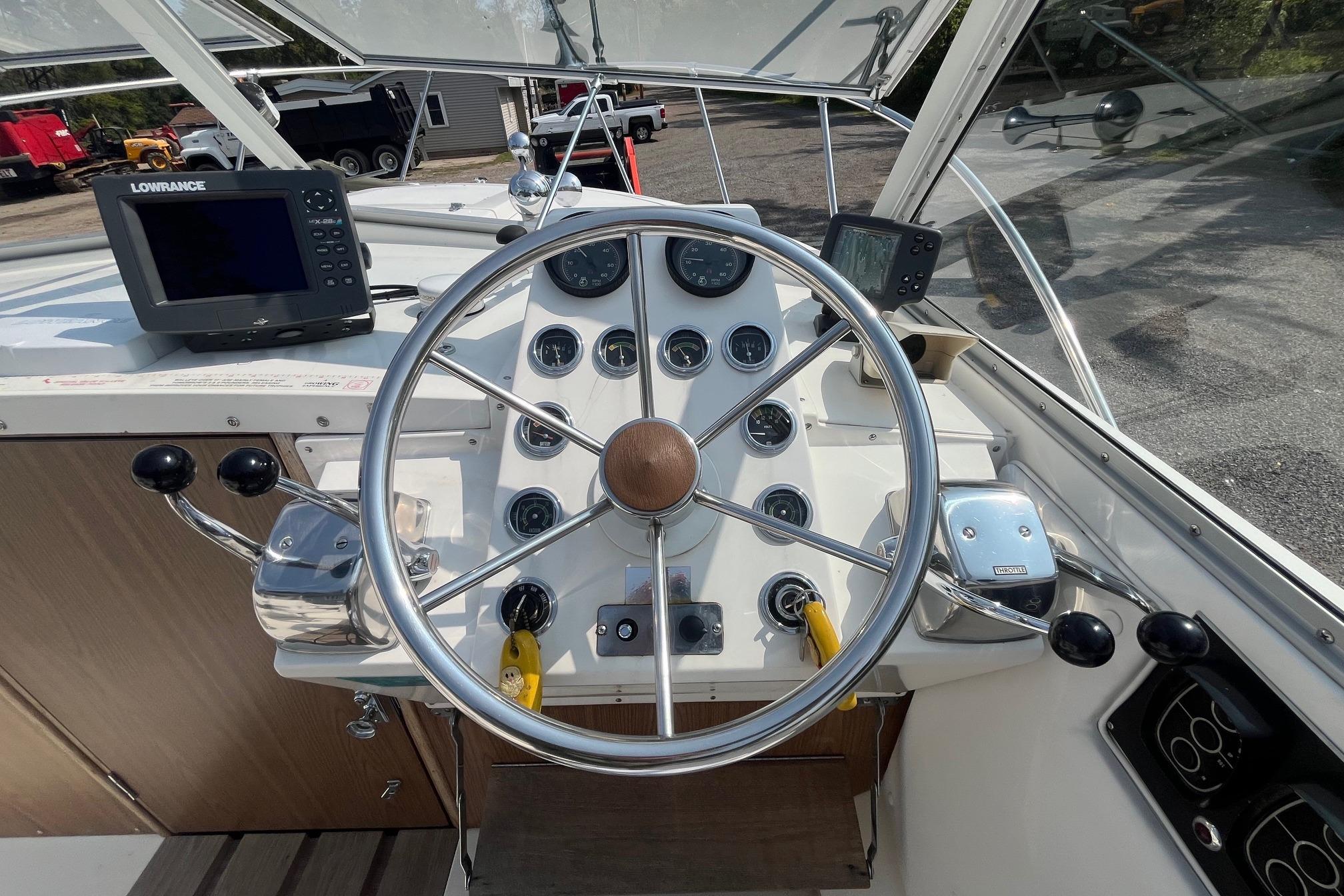 1975 Bertram 26 Moppie boat dashboard with steering wheel and navigation equipment.