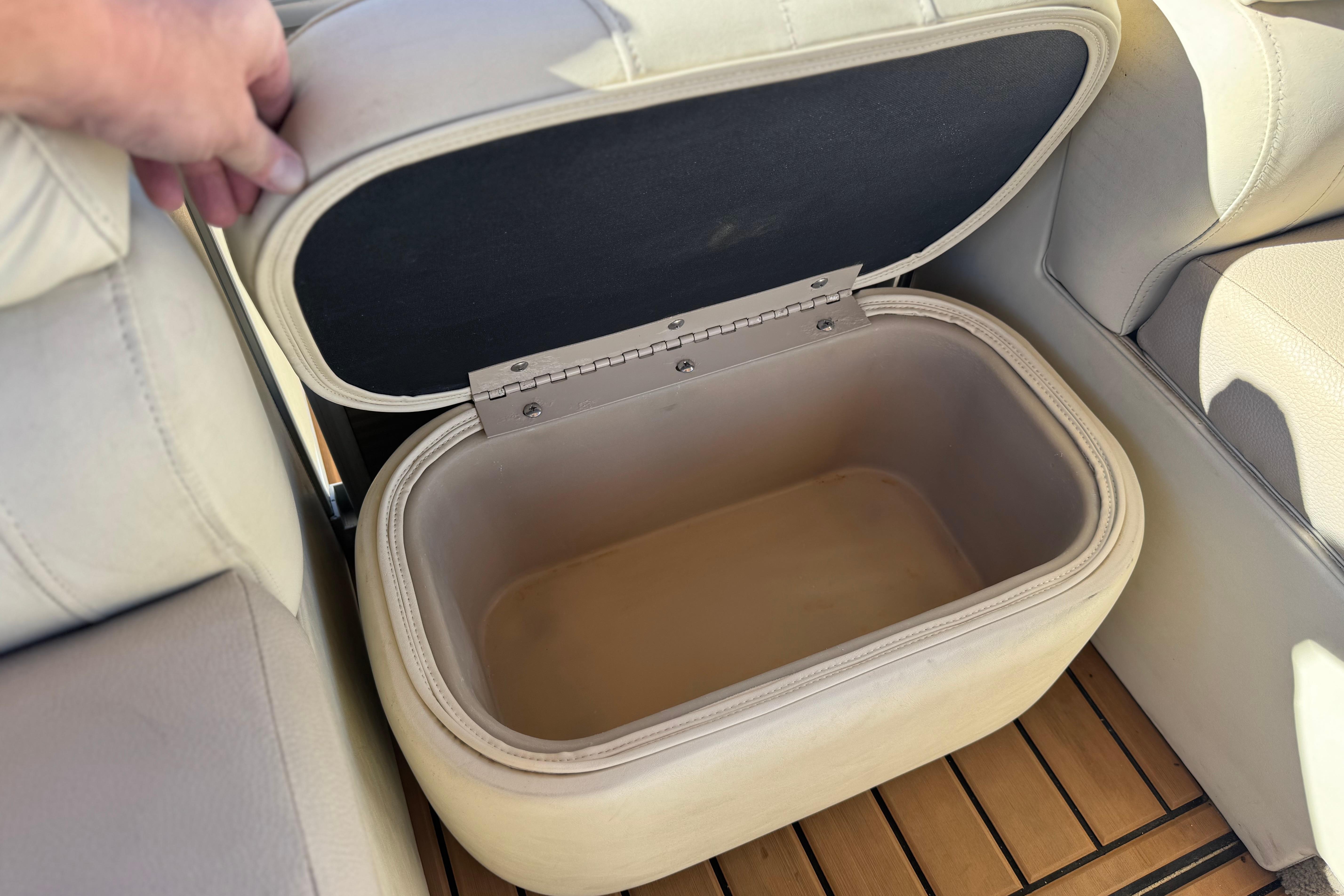 Open storage compartment in 2013 Bennington 2575QCW I/O boat, featuring beige upholstery.