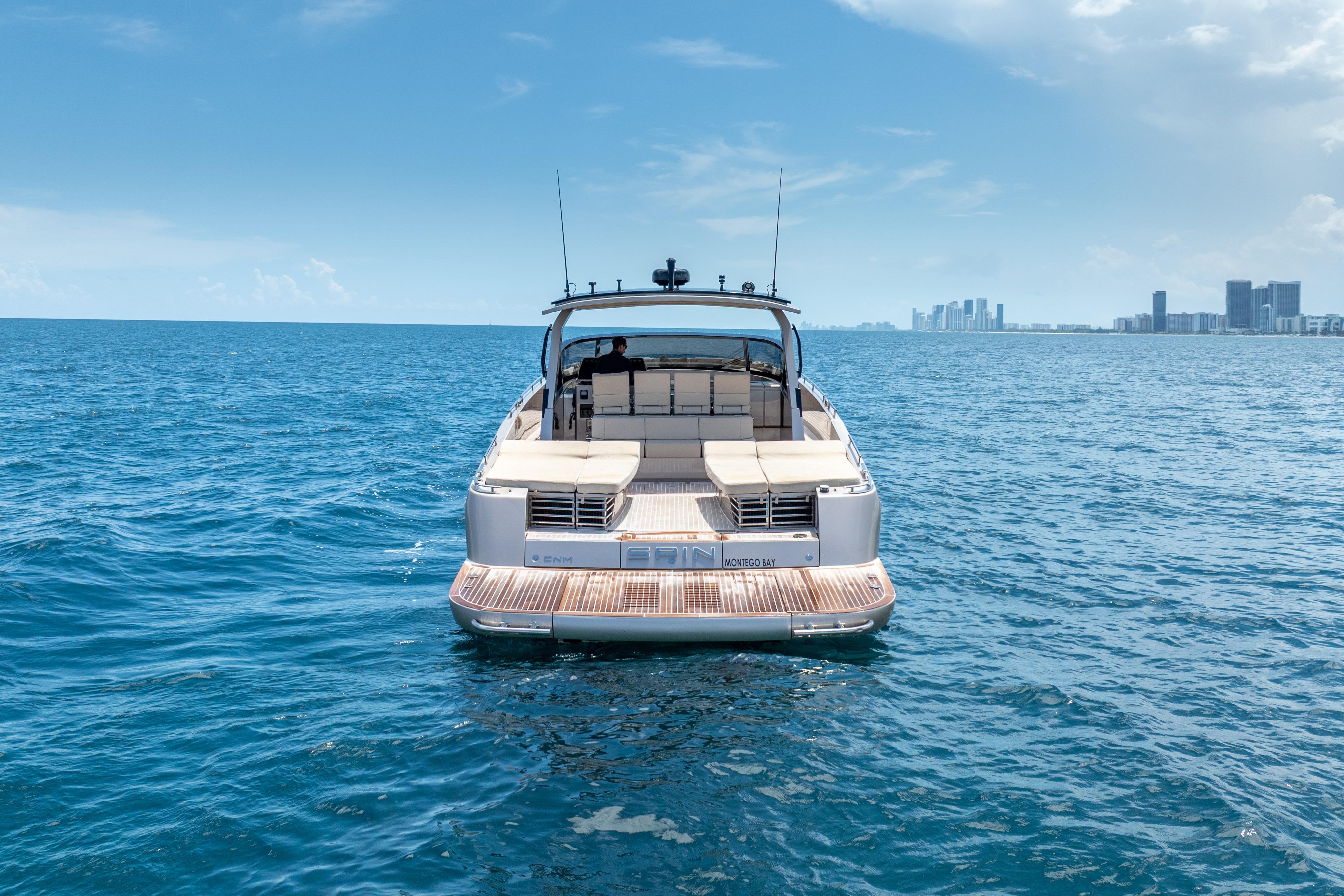 Luxury CNM Continental 54 yacht cruising on open sea, city skyline in background.