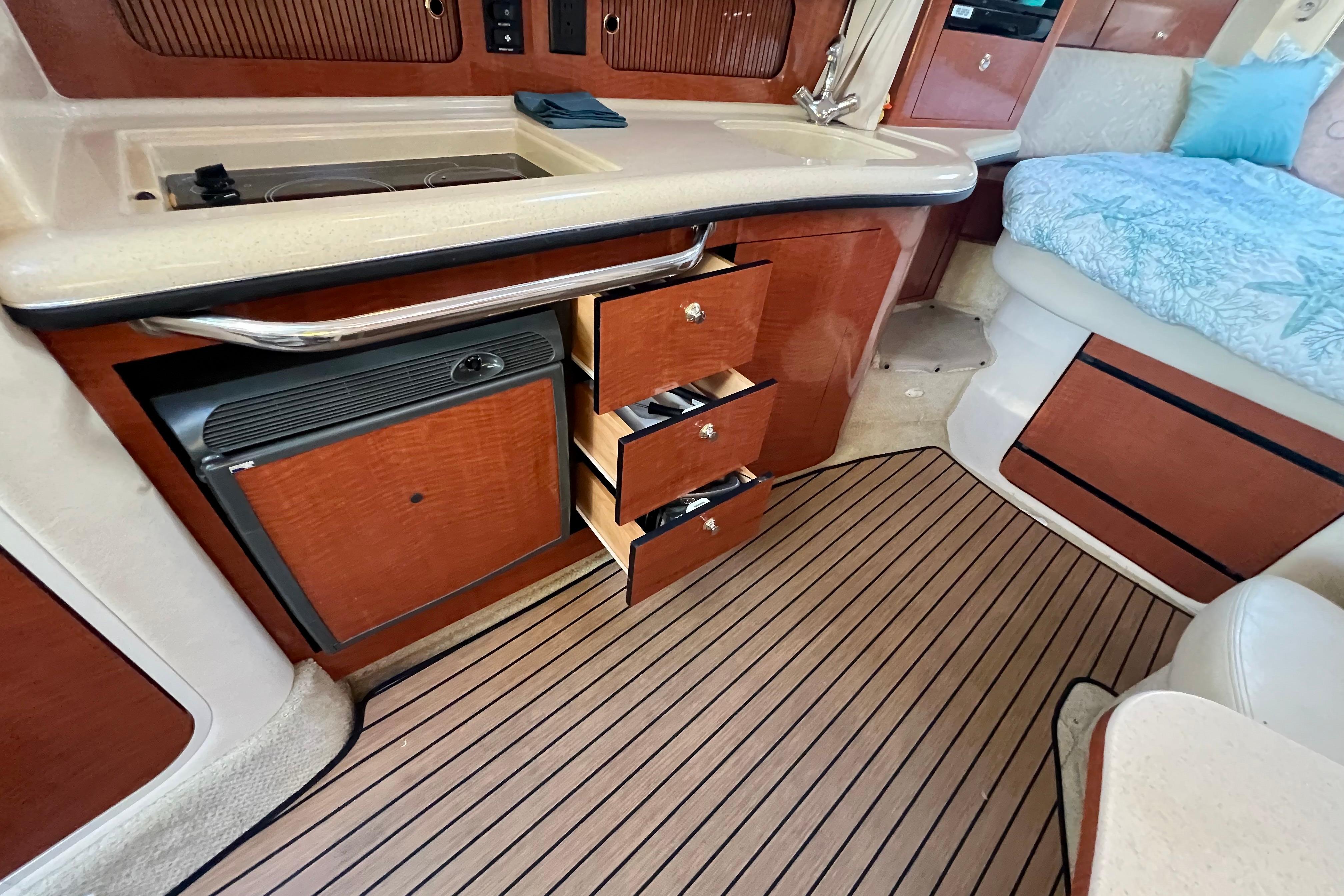 Interior of 2004 Sea Ray 320 Sundancer with kitchenette and open drawers.