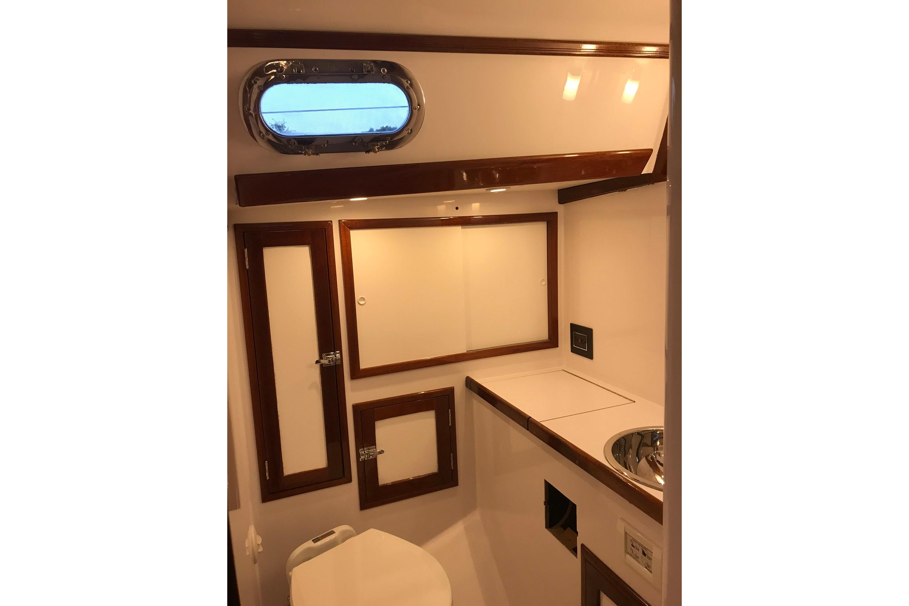 Interior of 1970 Hinckley Bermuda 40 yacht bathroom with wooden accents and porthole window.