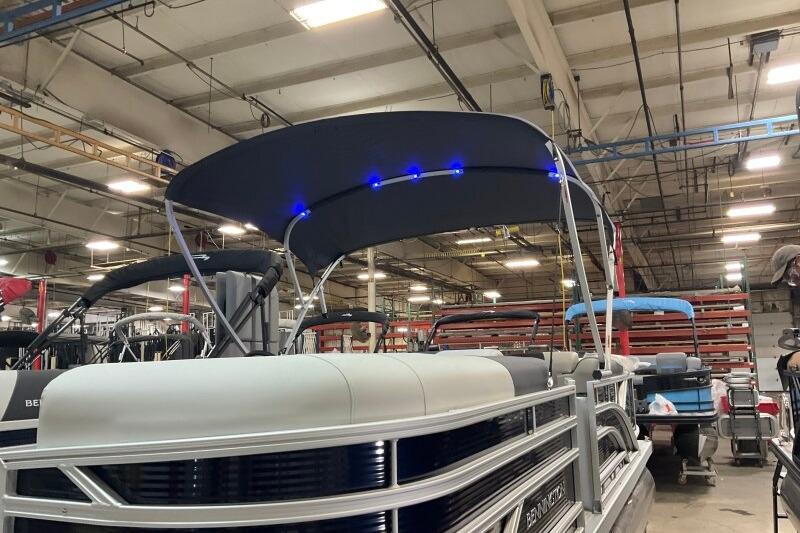 2026 Bennington 22 SSRSF pontoon boat with blue LED canopy lights in a factory setting.