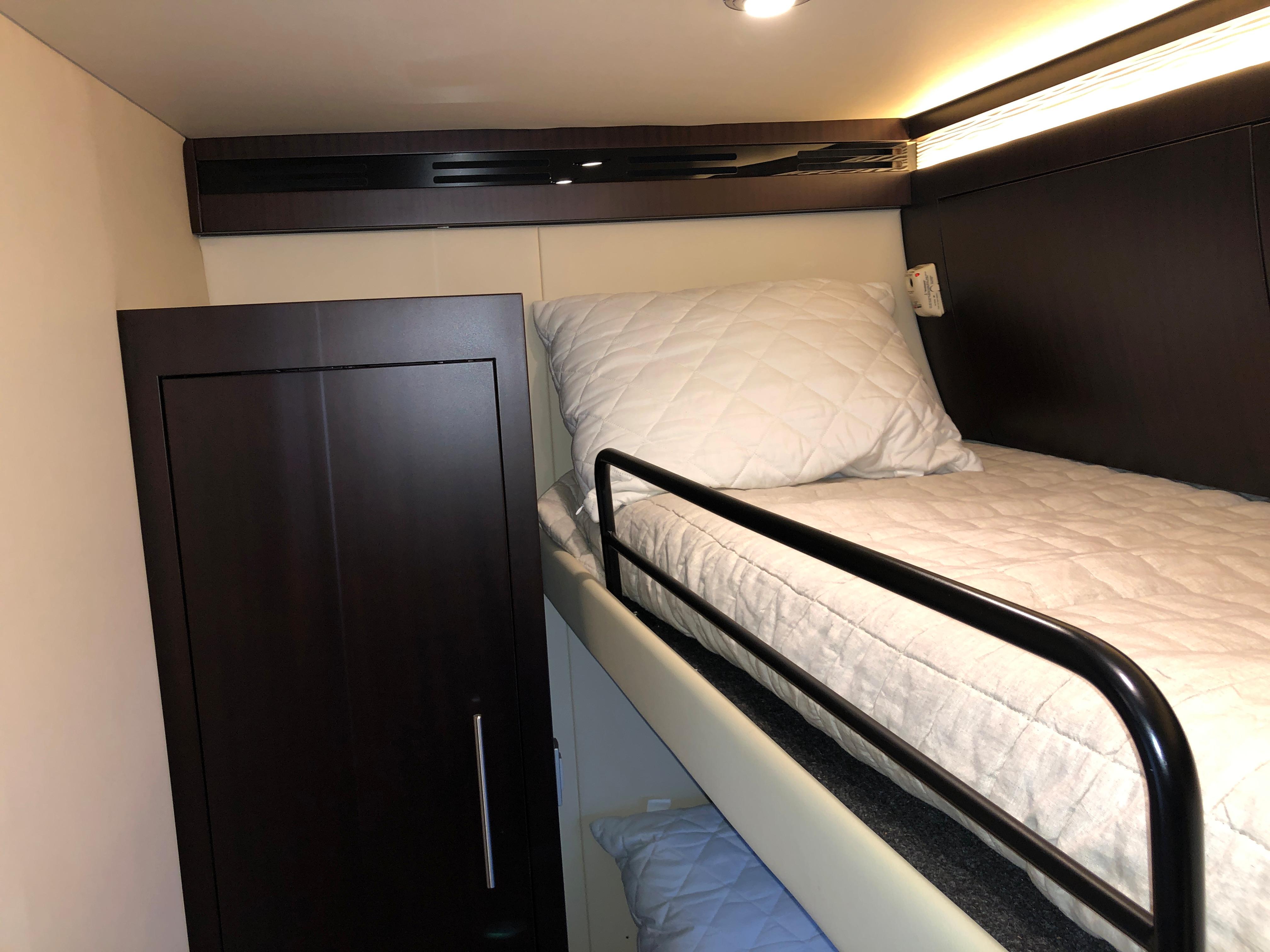Bunk bed in 2017 Regal 53 Sport Coupe yacht interior, featuring dark wood and modern design.