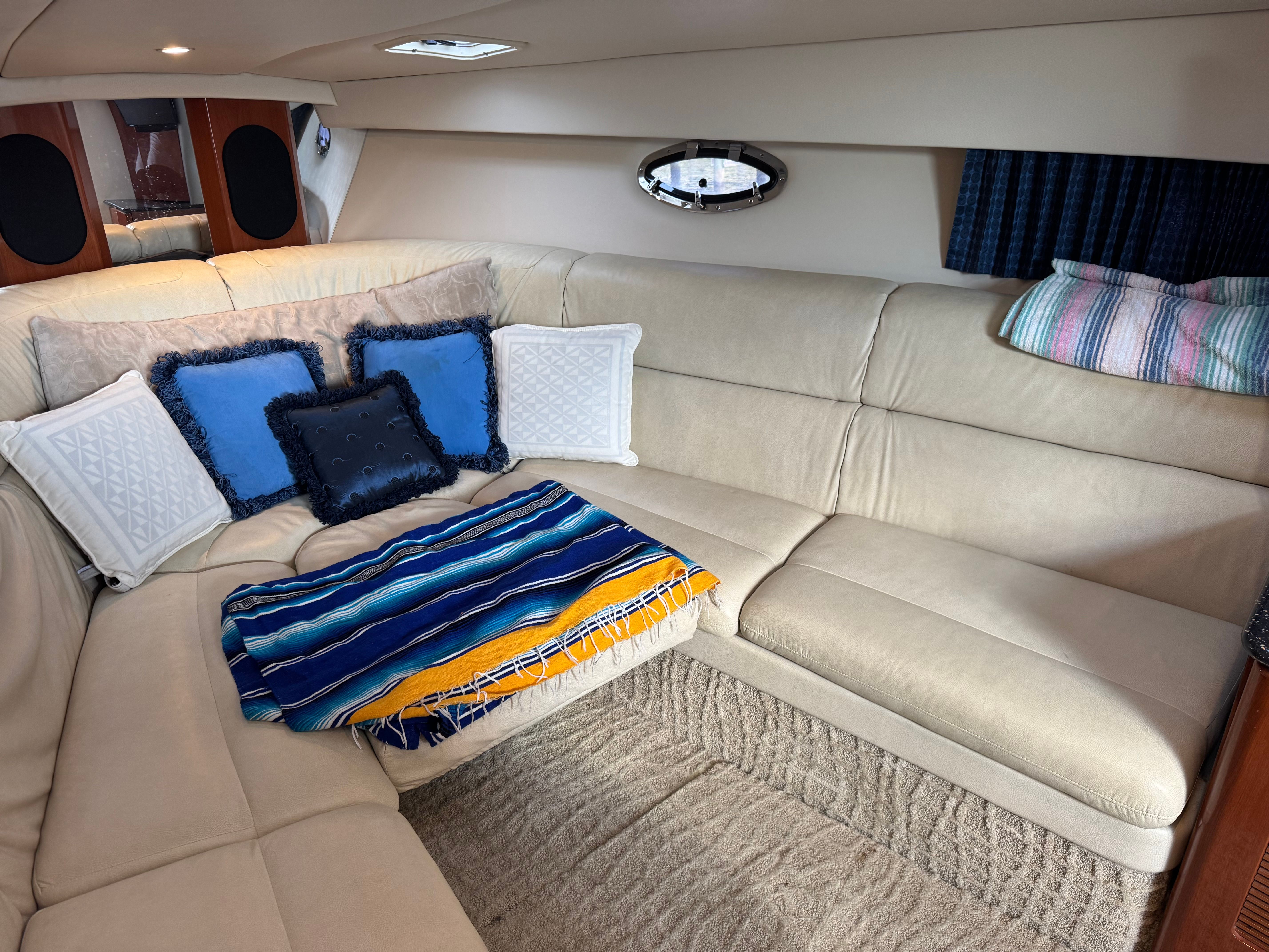 Interior of a luxurious boat cabin with beige leather sofas and colorful cushions.