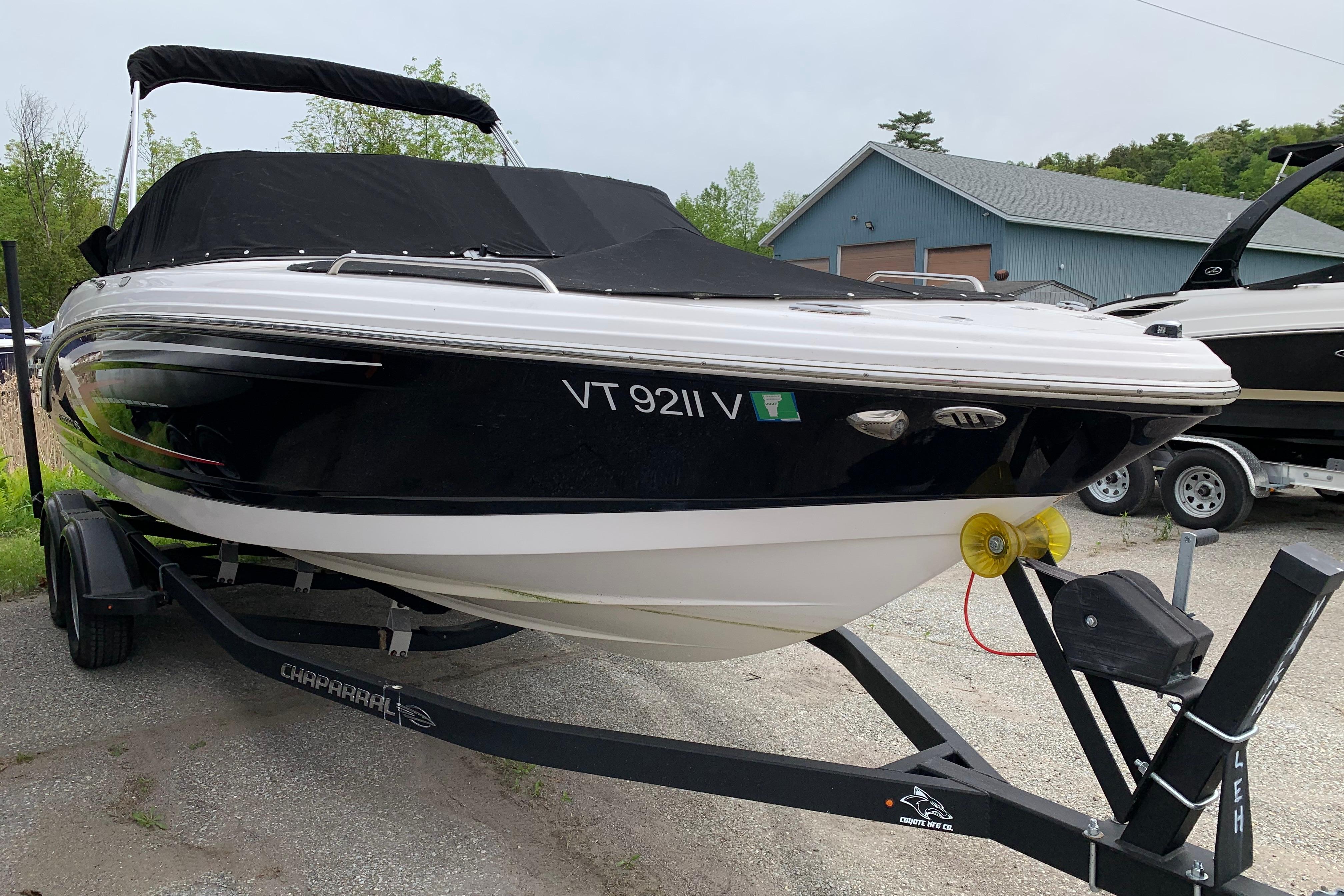 2022 Chaparral 23 SSi boat on trailer, black cover, parked outdoors.