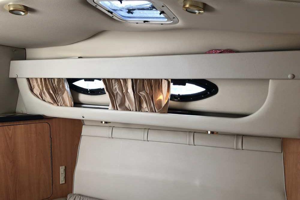 Interior of 1999 Regal Commodore 2760 boat with porthole windows and curtains.