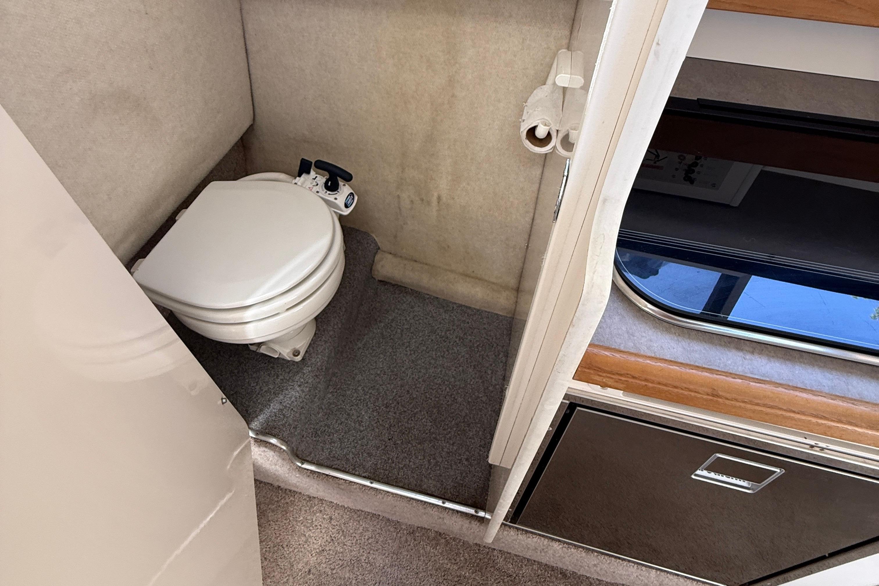 1997 Bayliner 2452 Ciera Express boat interior with compact marine toilet and storage area.