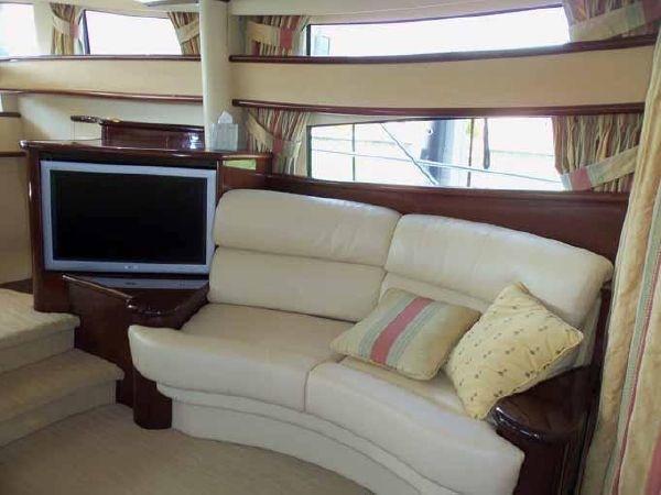 Luxurious interior of 2004 Neptunus 56 Flybridge yacht with cream leather sofa and TV.
