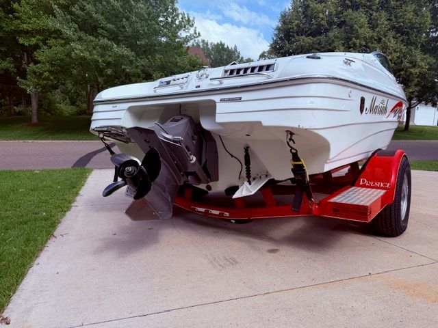 A 2001 Mariah Shabah boat on a red trailer, parked on a driveway.