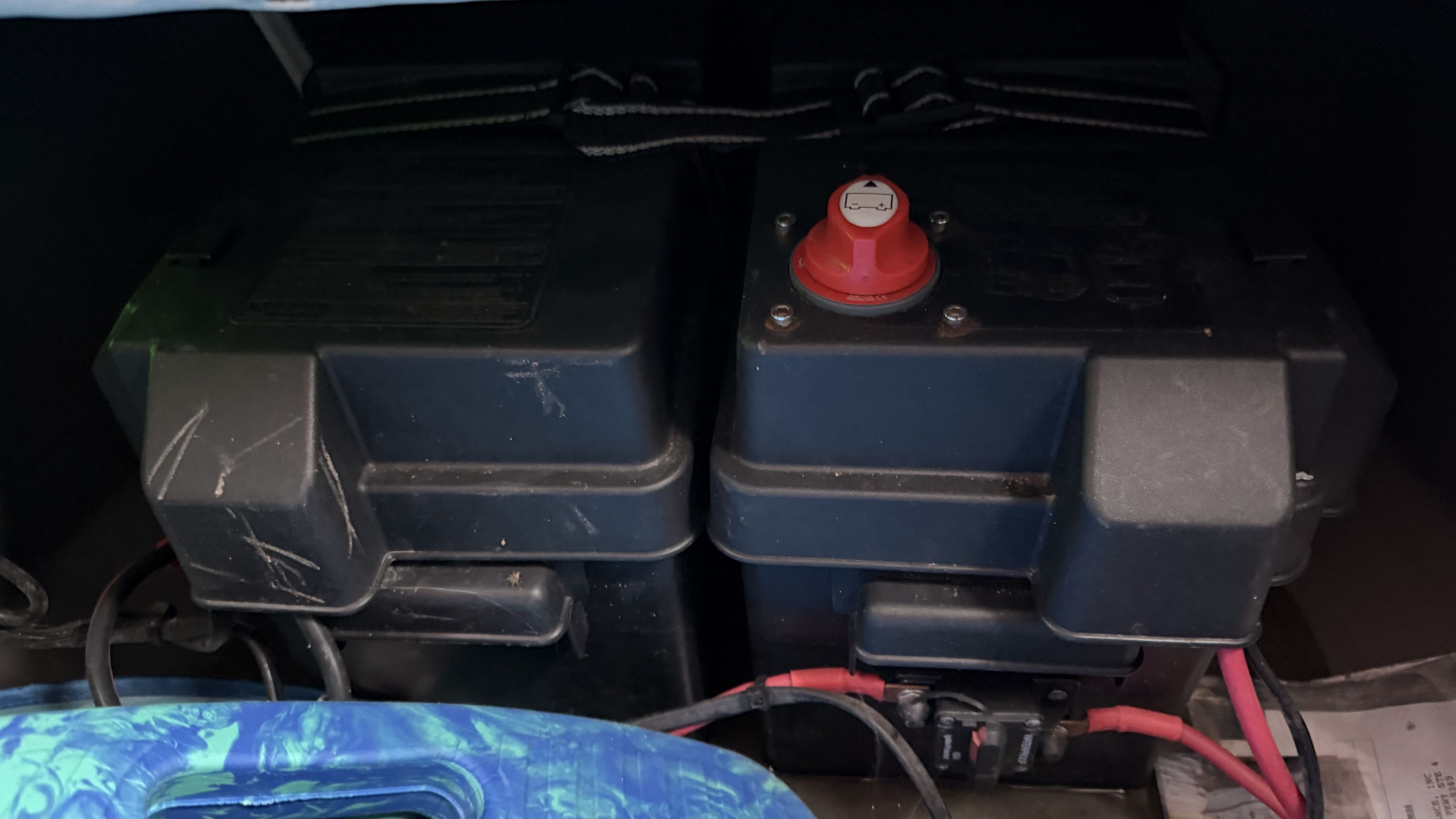 Two black battery boxes with a red switch, surrounded by cables.