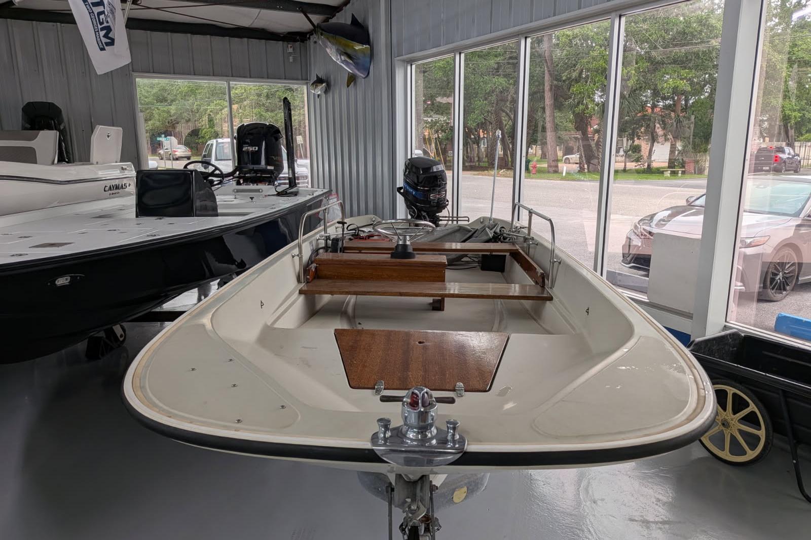 1978 Boston Whaler 15 SPORT boat displayed indoors with wooden seating and motor.