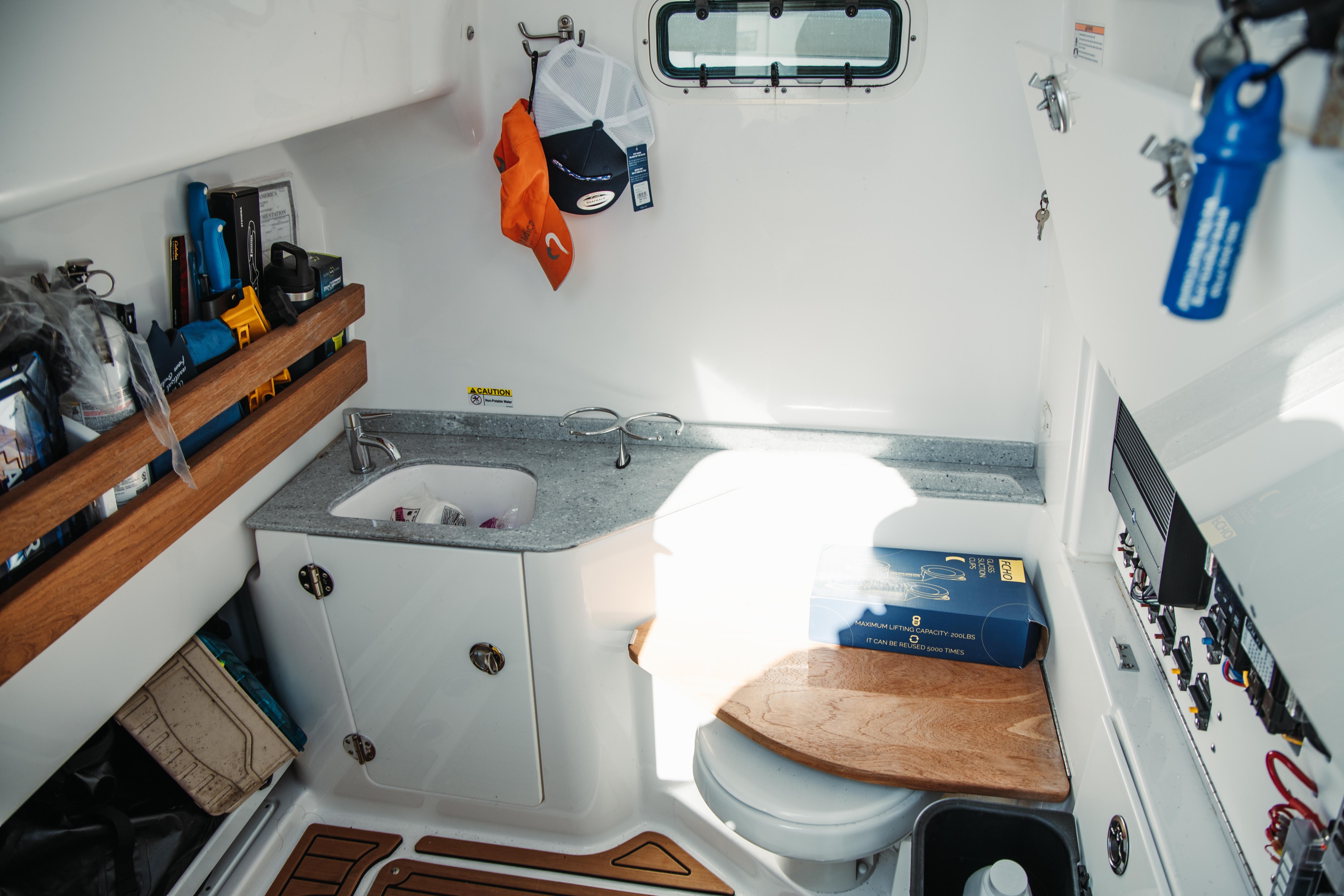 2024 Everglades 315 Center Console cabin with sink, storage, and wooden accents.