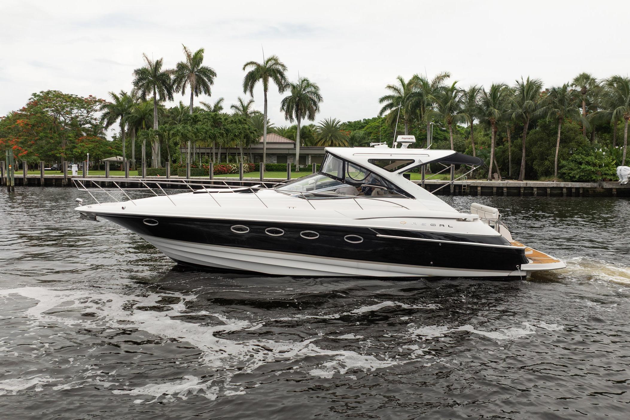 2008 Regal Commodore 4460 yacht cruising on a scenic waterway with palm trees.