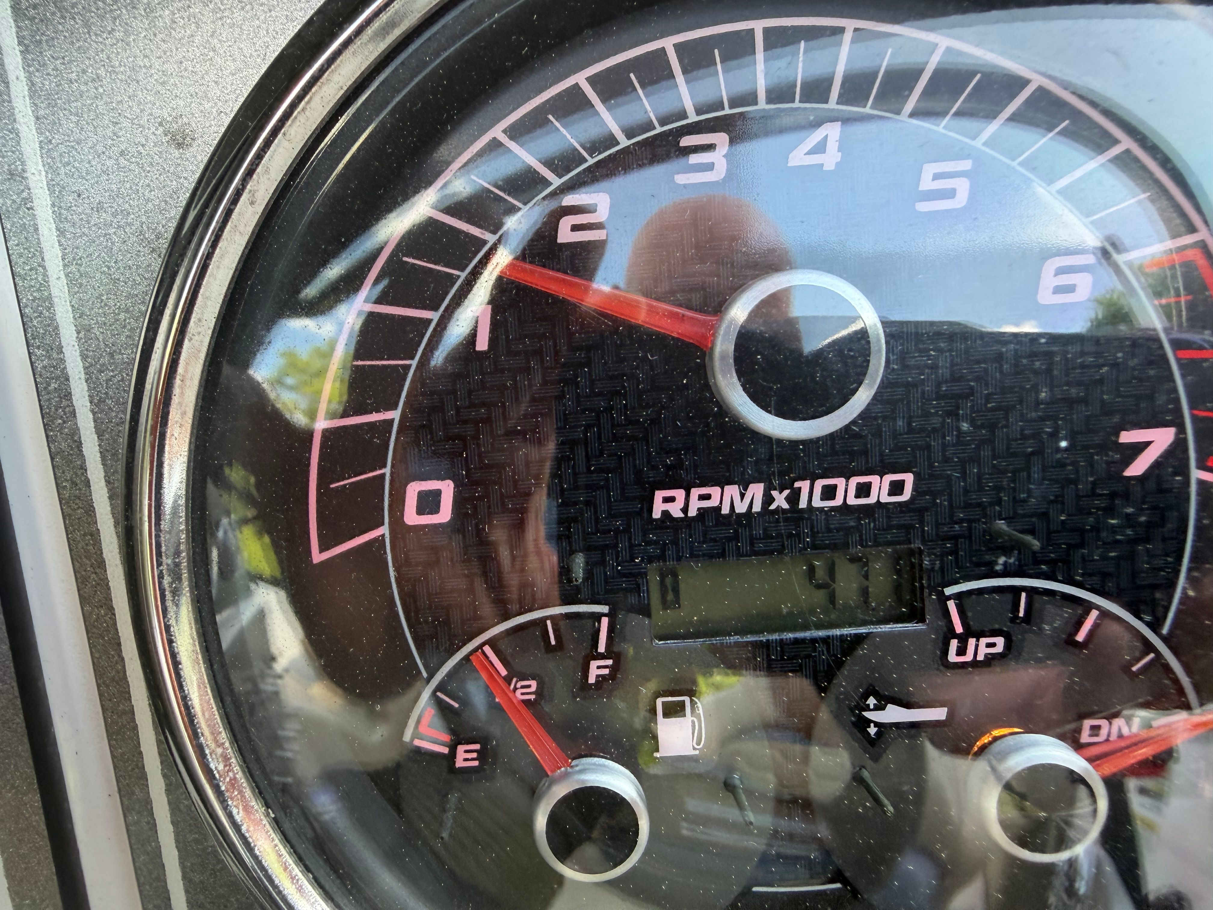 Close-up of a tachometer with digital display and red markings.