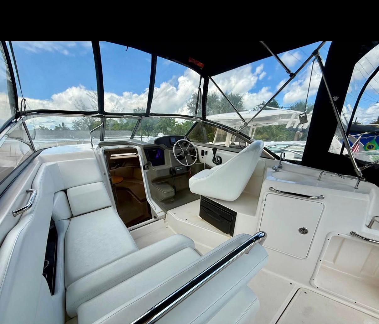 The image shows the cockpit of a 2008 Regal 2565 Window Express with white seating and clear skies.