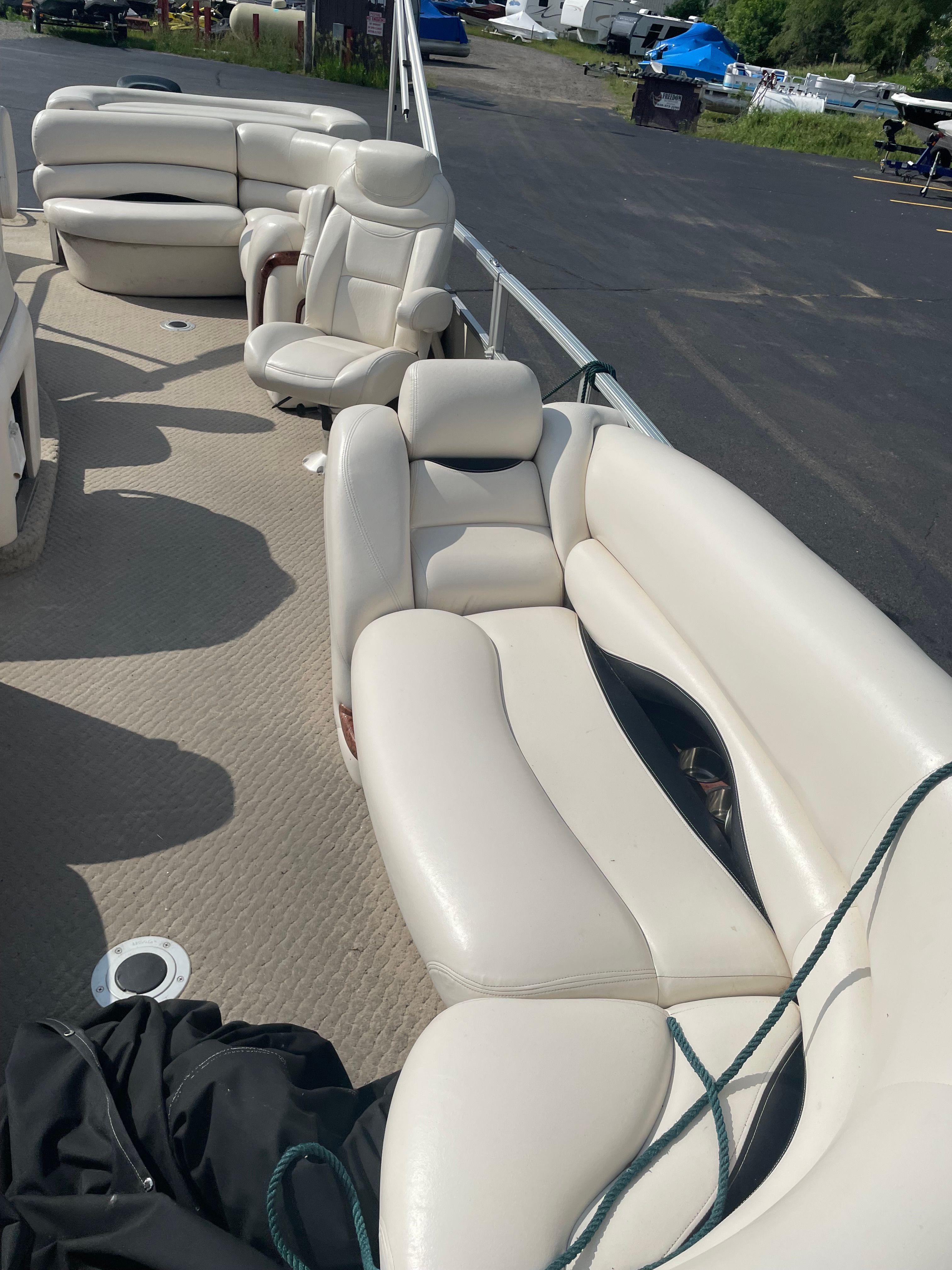 Interior of a party boat with beige leather seats and carpeted floor.