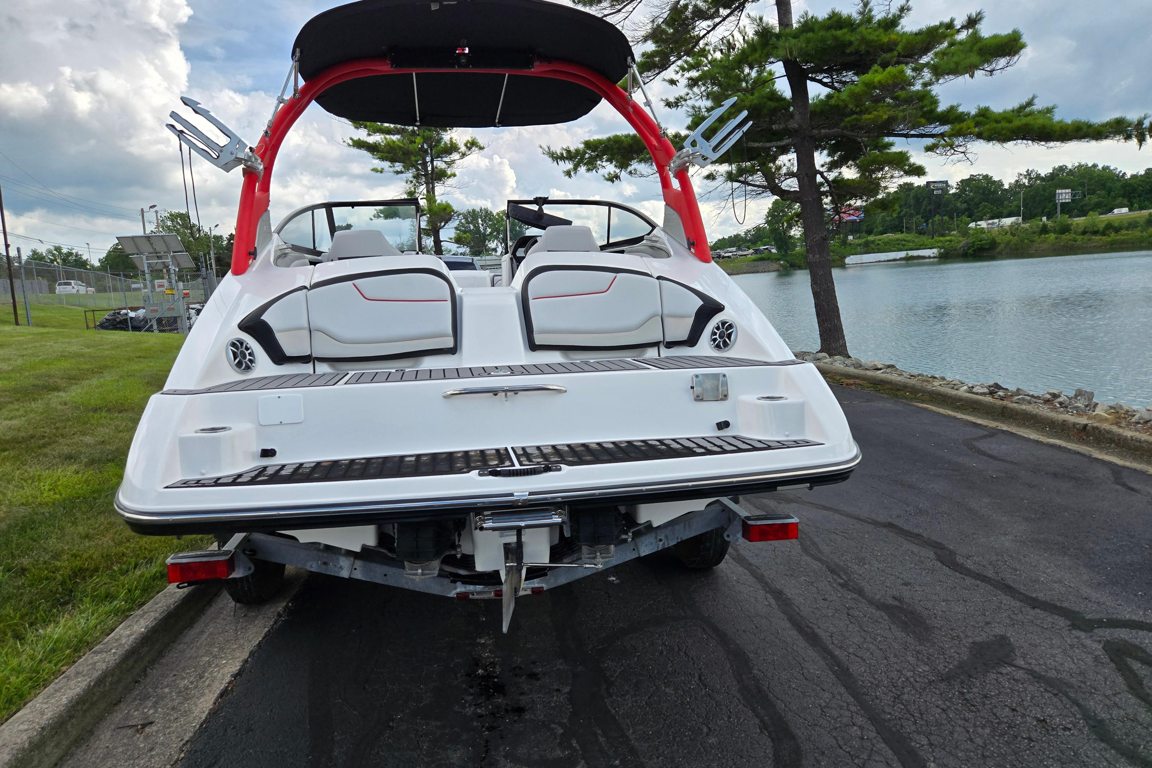 2018 Yamaha Boats 212X on trailer by a lakeside, showcasing rear deck and seating.