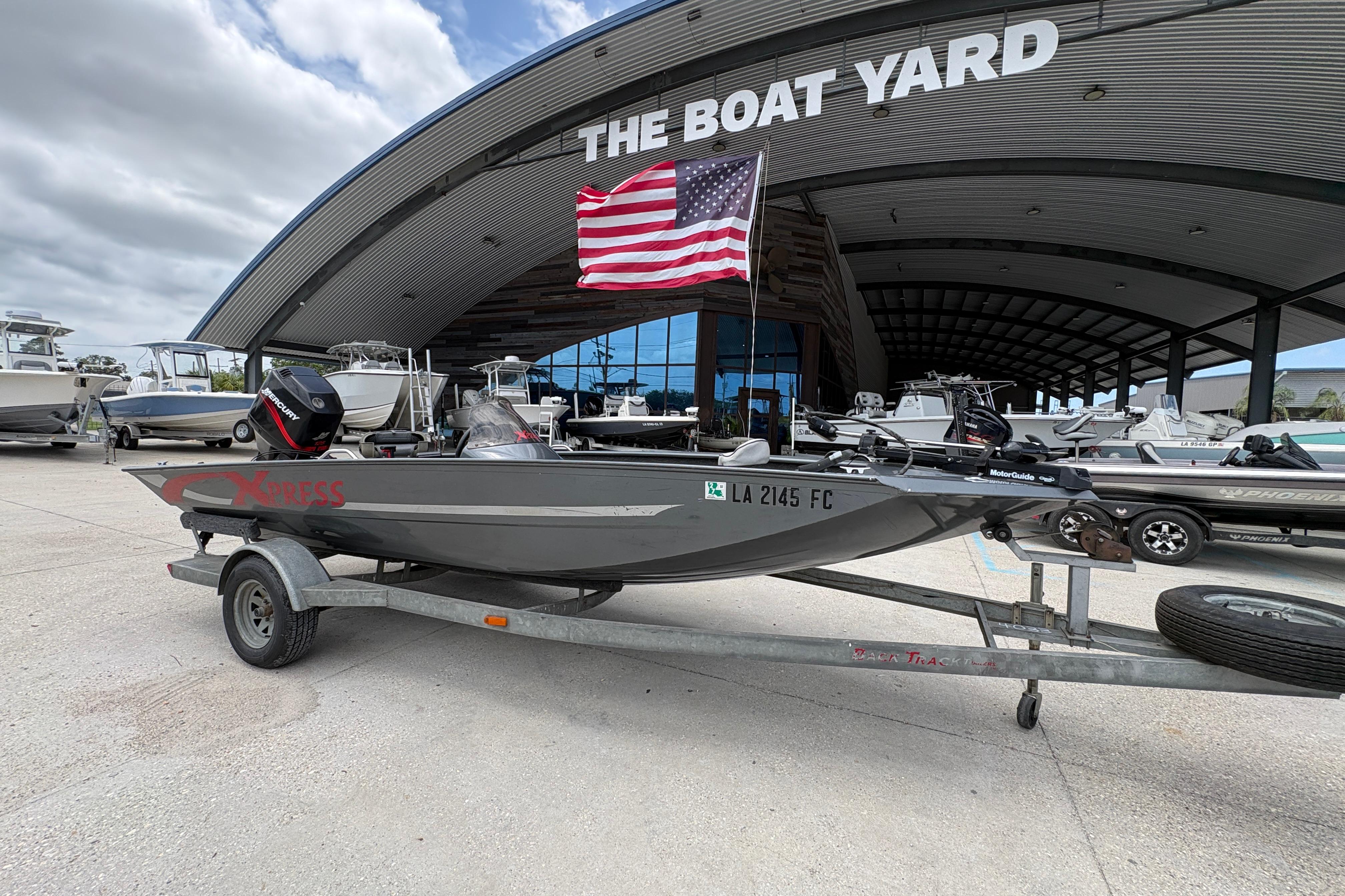 2000 Xpress X18 boat on trailer at The Boat Yard, American flag above.