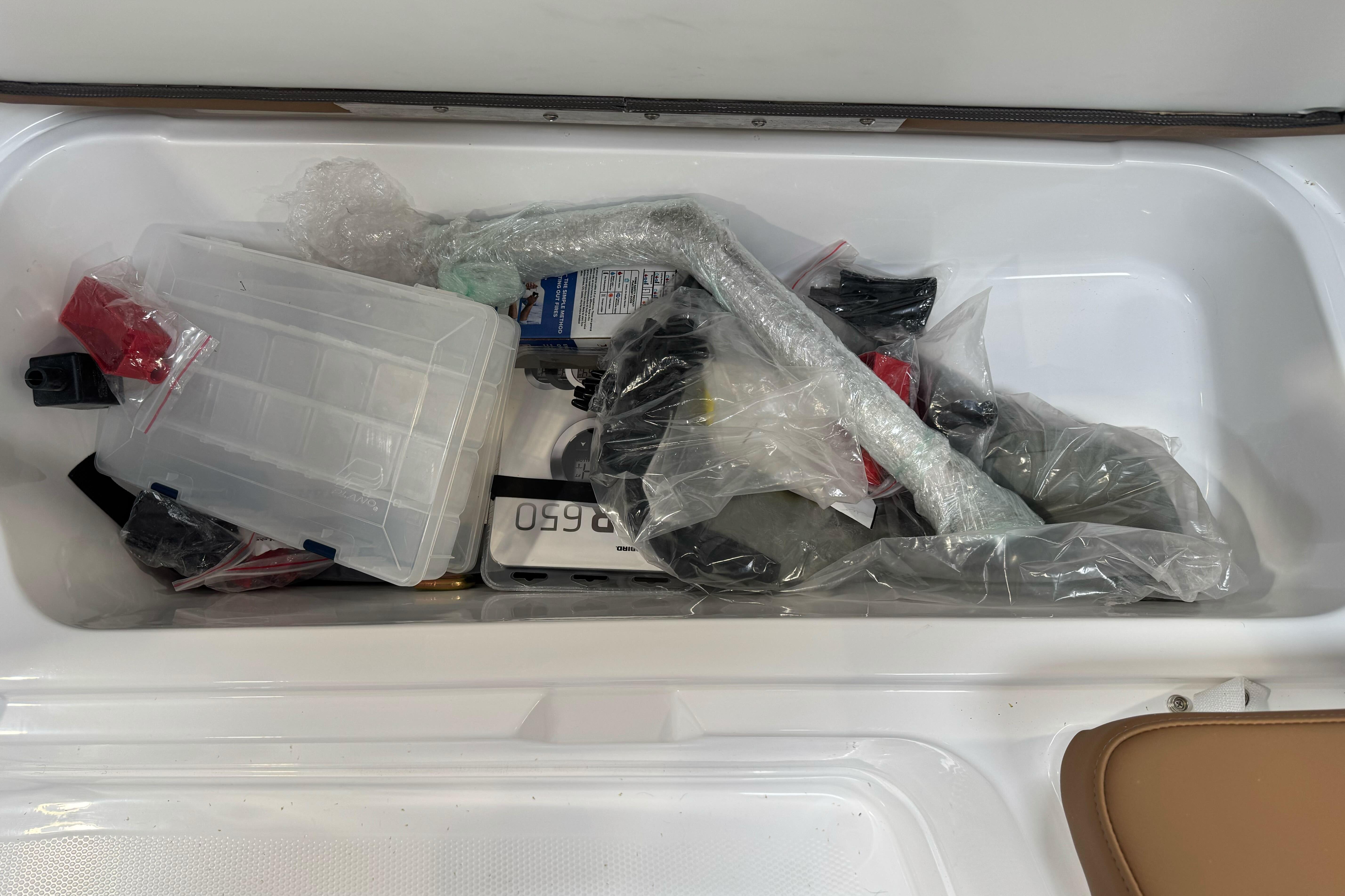 Storage compartment in 2026 Tahoe 2150 boat filled with various packaged items.