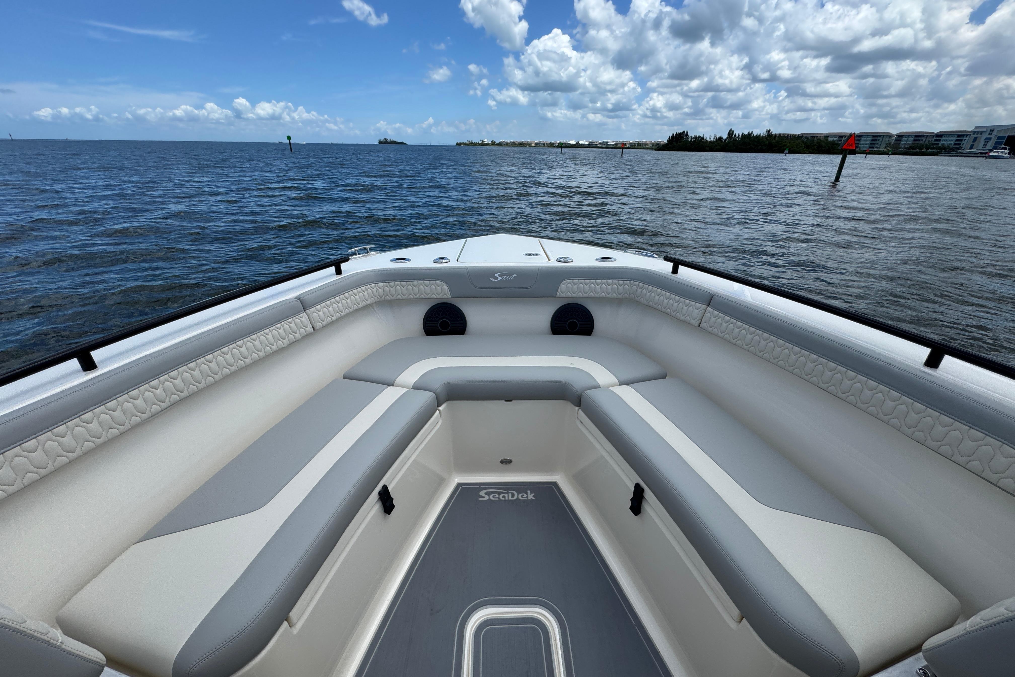 2026 Scout 260 LXF boat interior with cushioned seating, on a calm ocean under a cloudy sky.