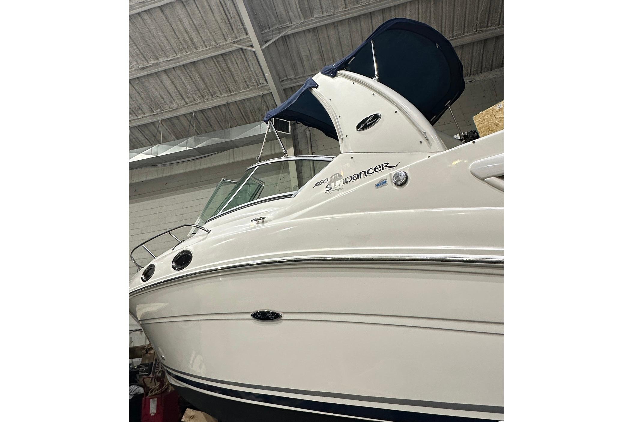 2007 Sea Ray Sundancer 260 boat with blue canopy in indoor storage.