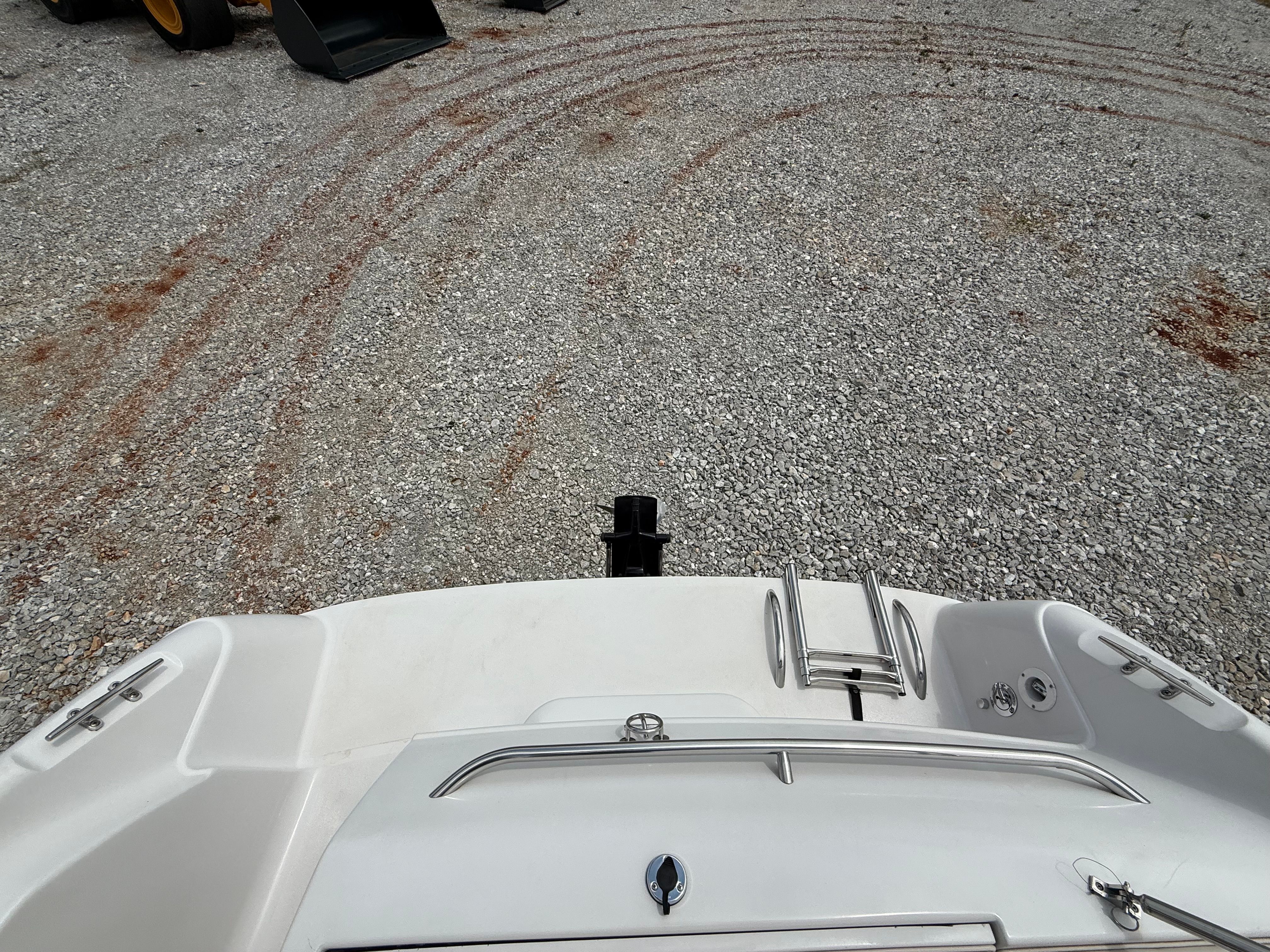 The image shows the stern of a boat on a gravel lot with a ladder.