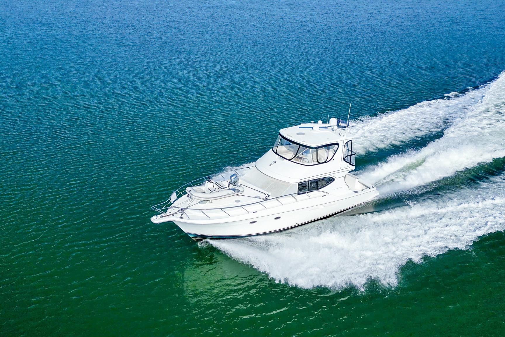 2004 Silverton 48 Convertible yacht cruising on open water, creating a wake.