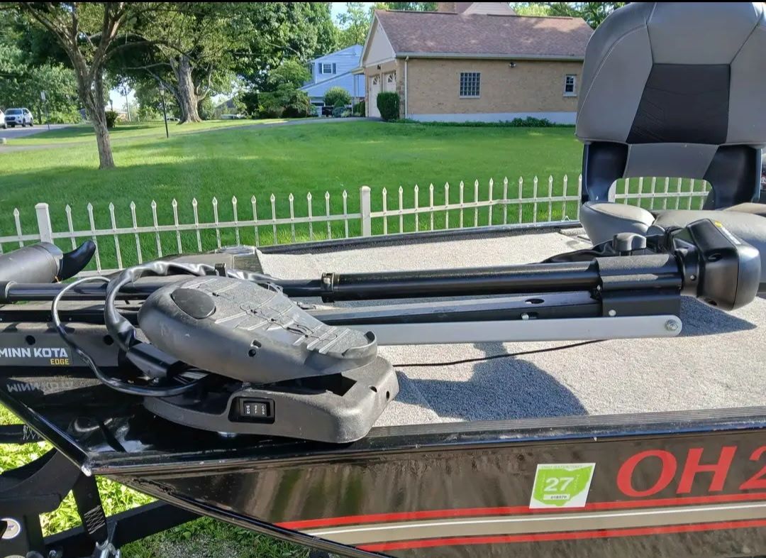 A 2024 Bass Tracker 50ELPT is on a lawn with a white fence in the background.