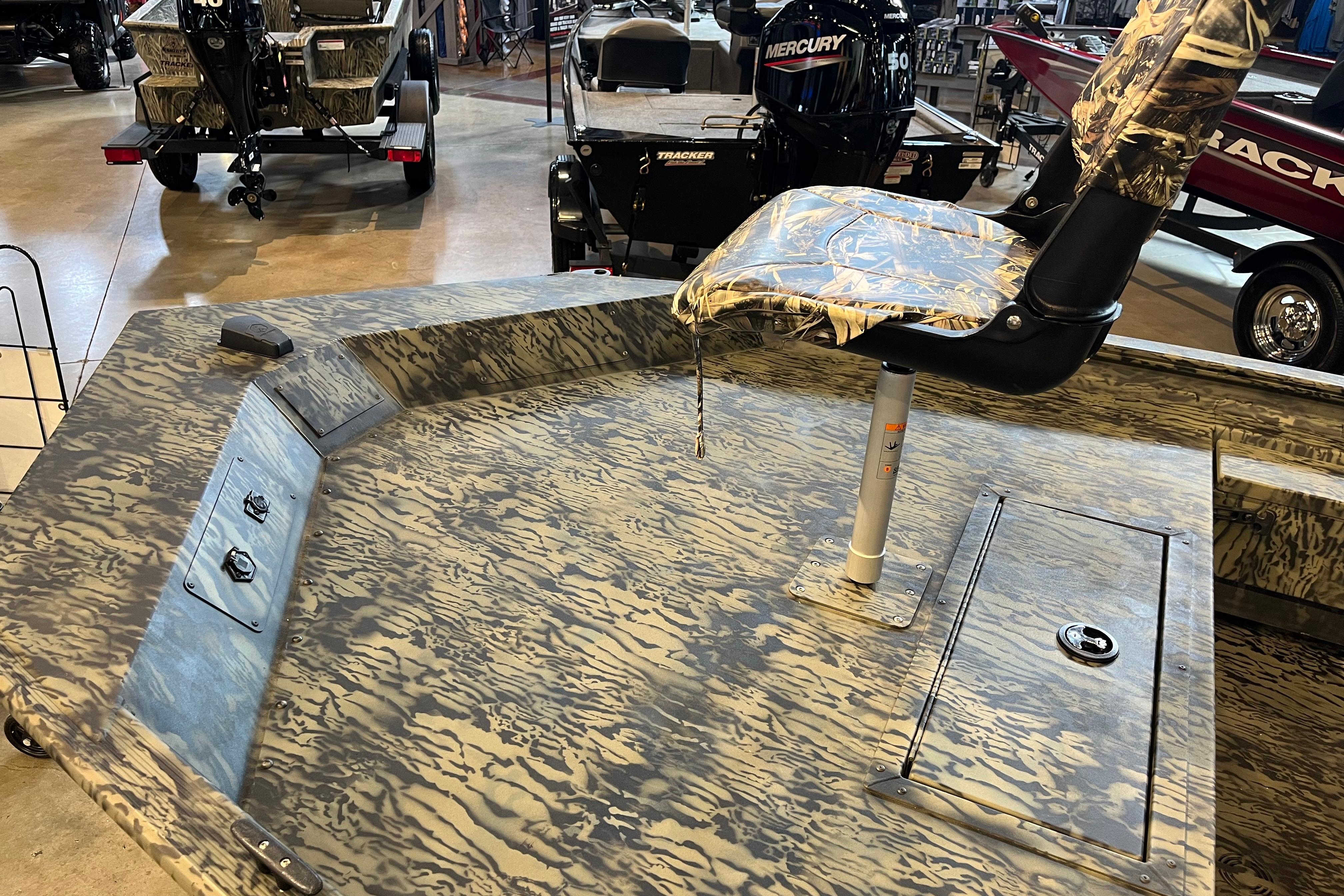 2026 Tracker Grizzly 1654 T Sportsman boat with camo seat and deck, displayed indoors.