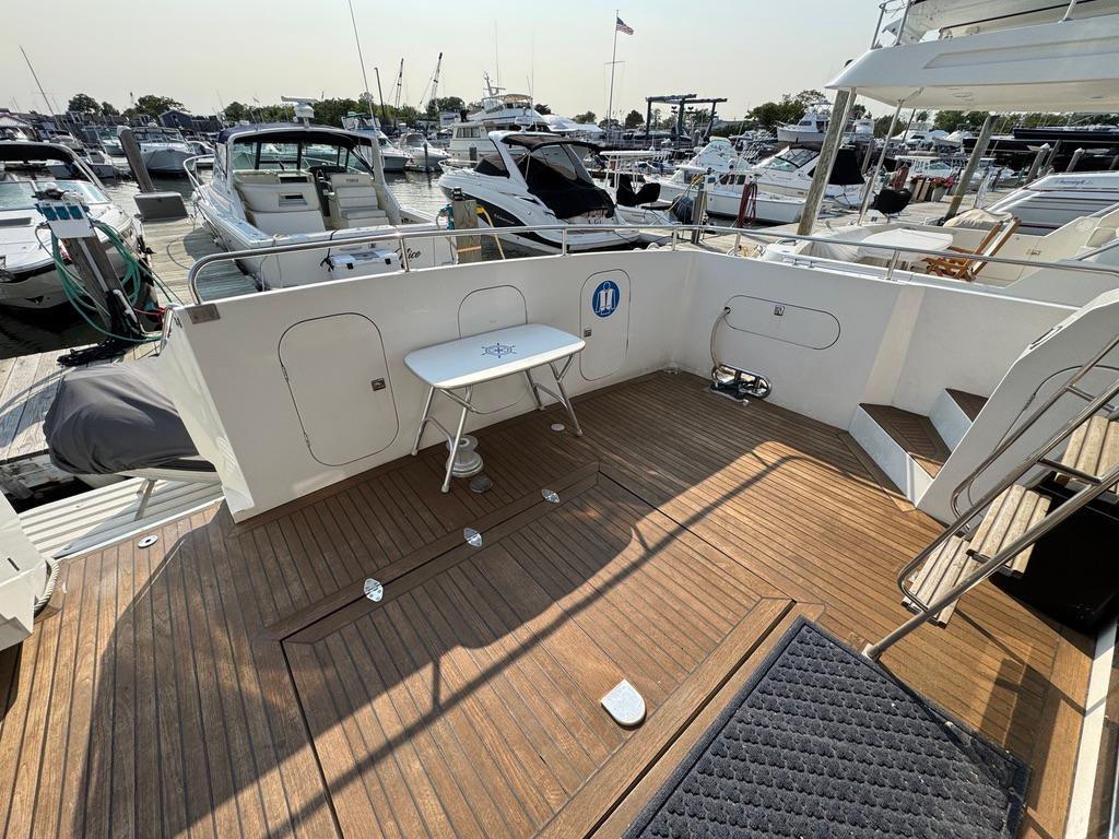 1989 Birchwood 62 Cockpit Motor Yacht with spacious wooden deck at marina.