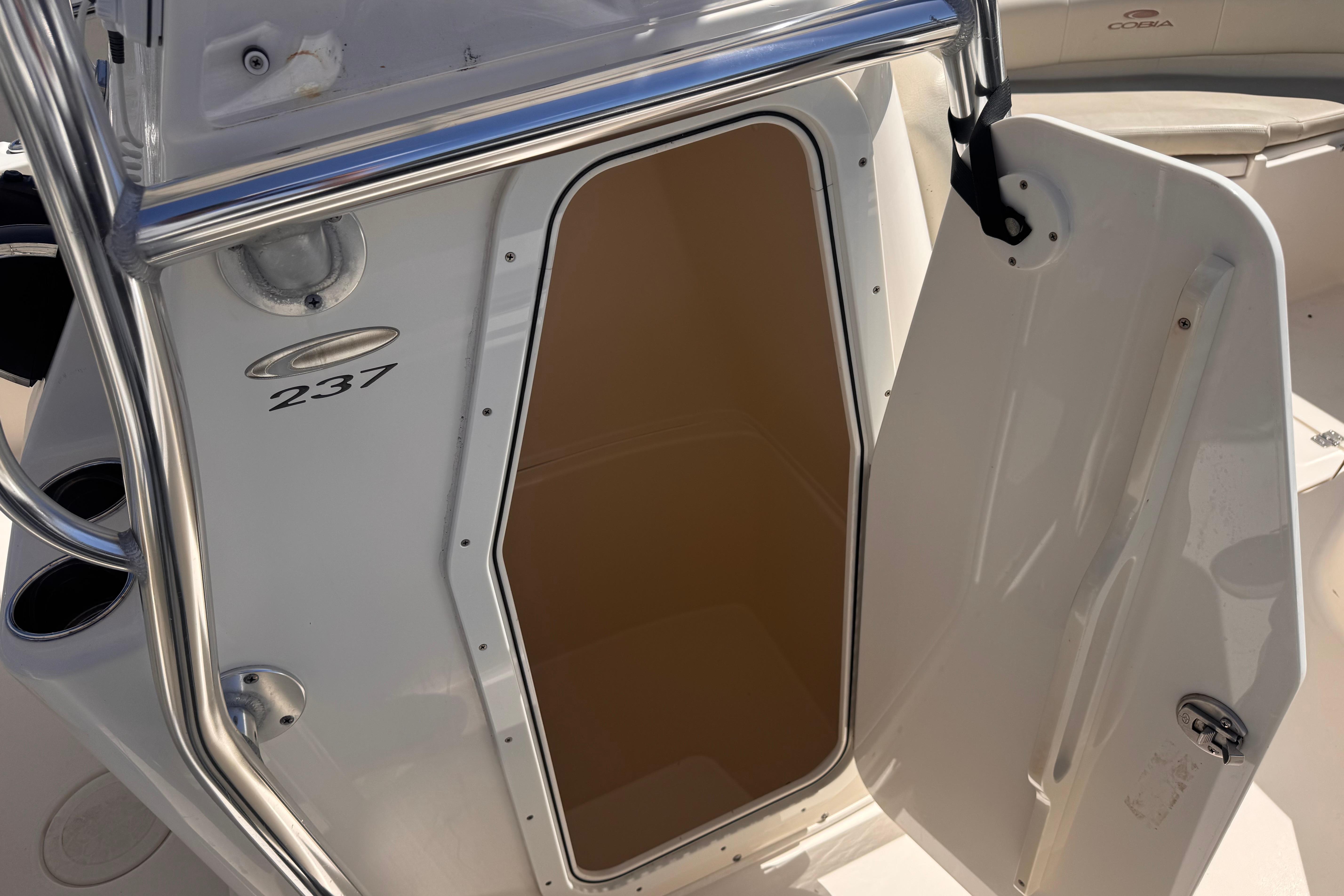 2023 Cobia 237 Center Console boat with open storage compartment door.