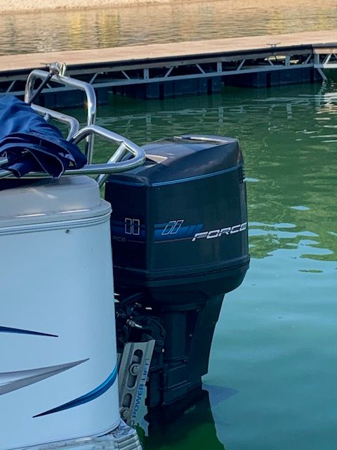 A boat with an outboard motor at the dock.