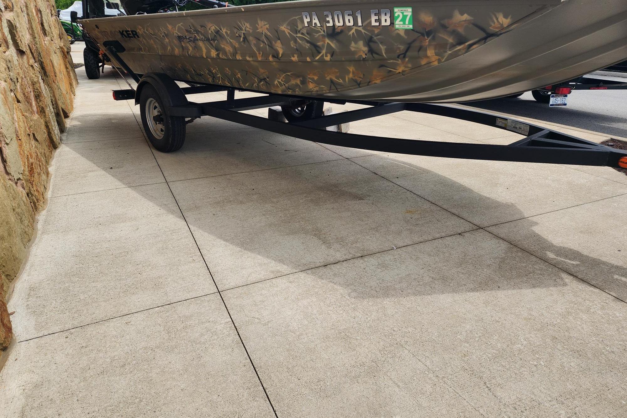 2022 GRIZZLEY 1654SPT boat on trailer, camouflage design, parked on concrete.