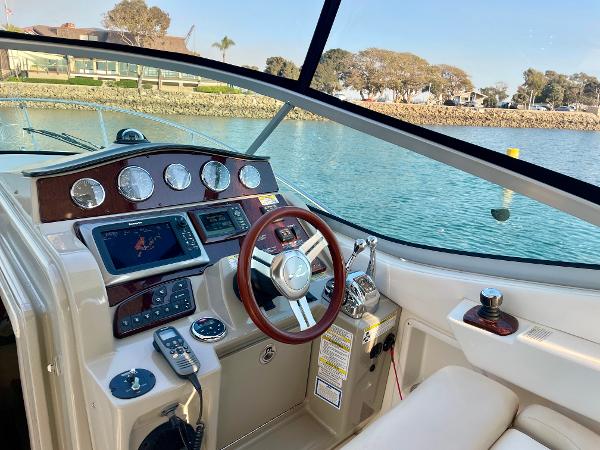 2014 Sea Ray 330 Sundancer cockpit with modern controls and scenic waterfront view.