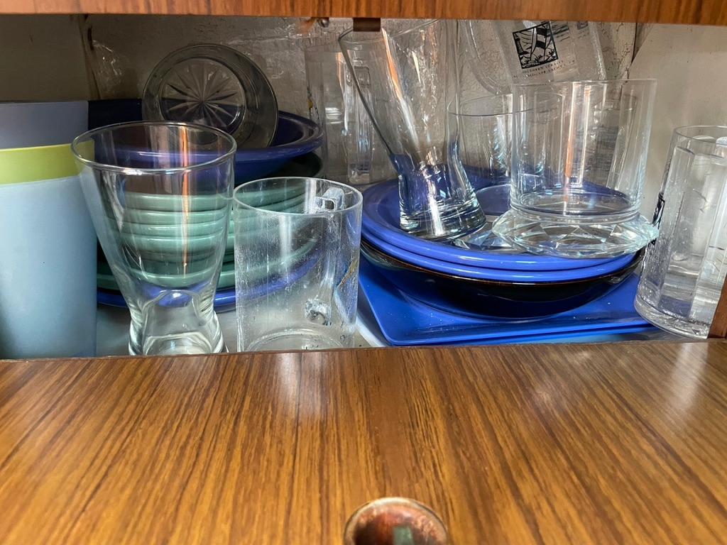 Glassware and blue dishes in a wooden cabinet on a 1973 Camper & Nicholsons 38.