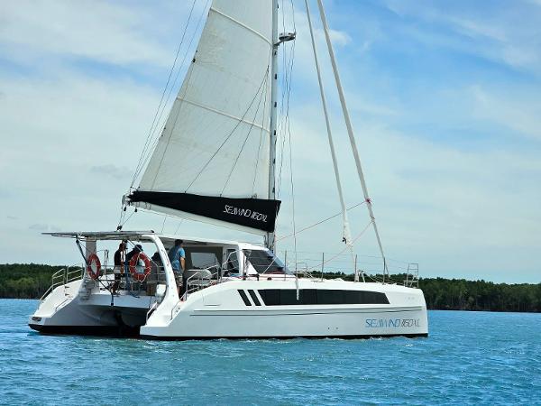 2025 Seawind 1160 XL catamaran sailing on calm blue waters under a clear sky.
