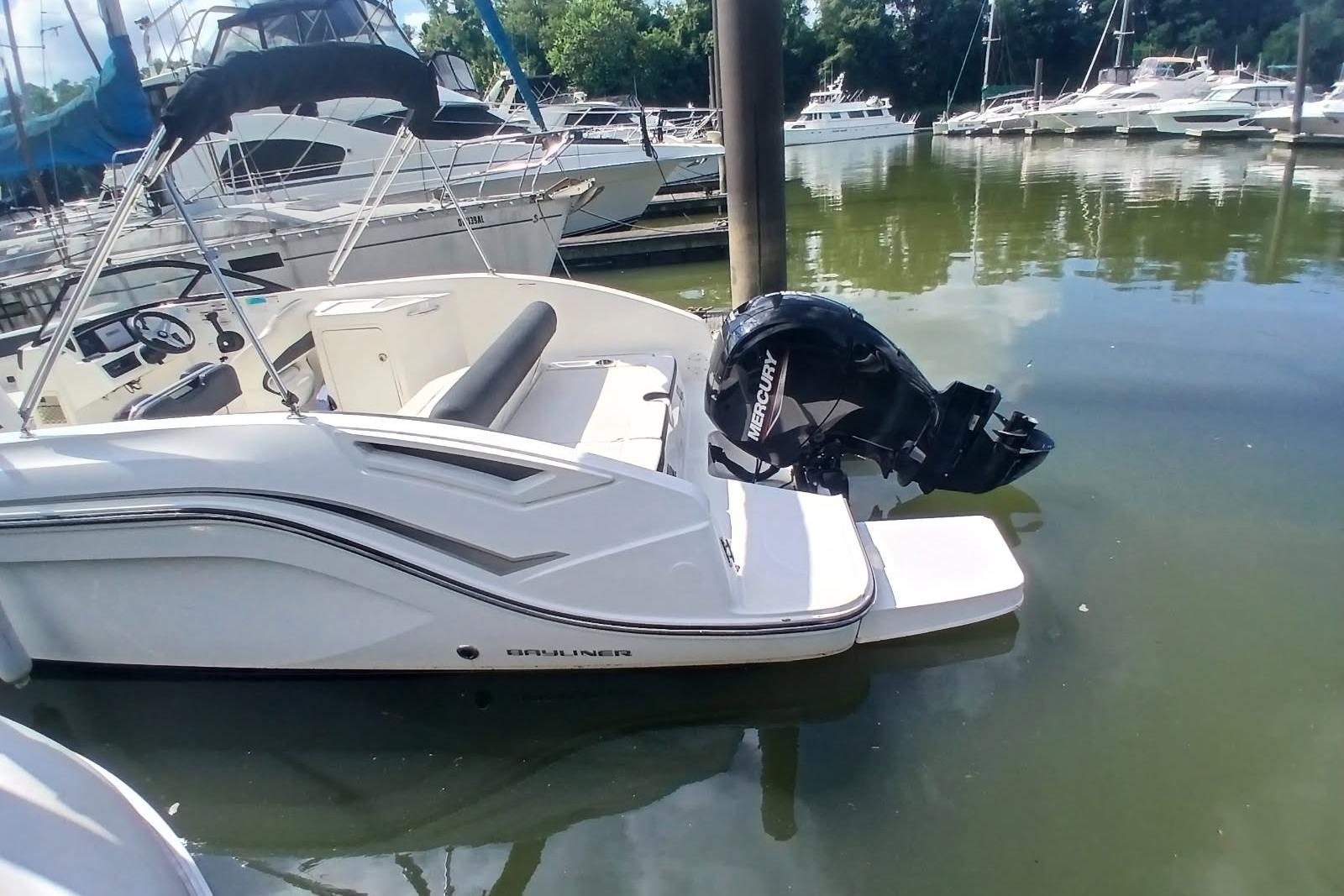 2023 Bayliner DX 2200 boat docked with Mercury outboard motor in a marina.