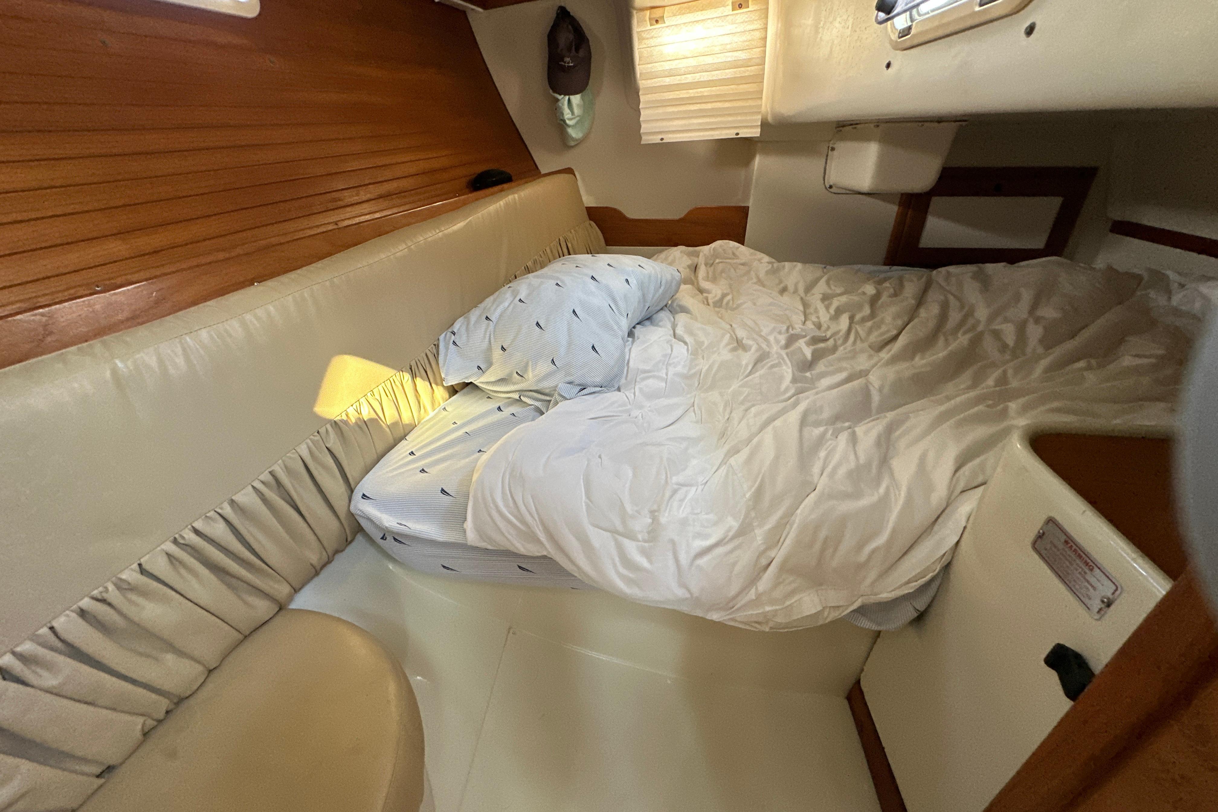Cozy cabin interior of a 1995 Catalina 320 sailboat with a neatly made bed.