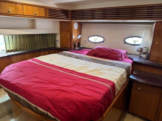 Interior of 2001 Carver 396 Motoryacht bedroom with bed and wooden cabinetry.