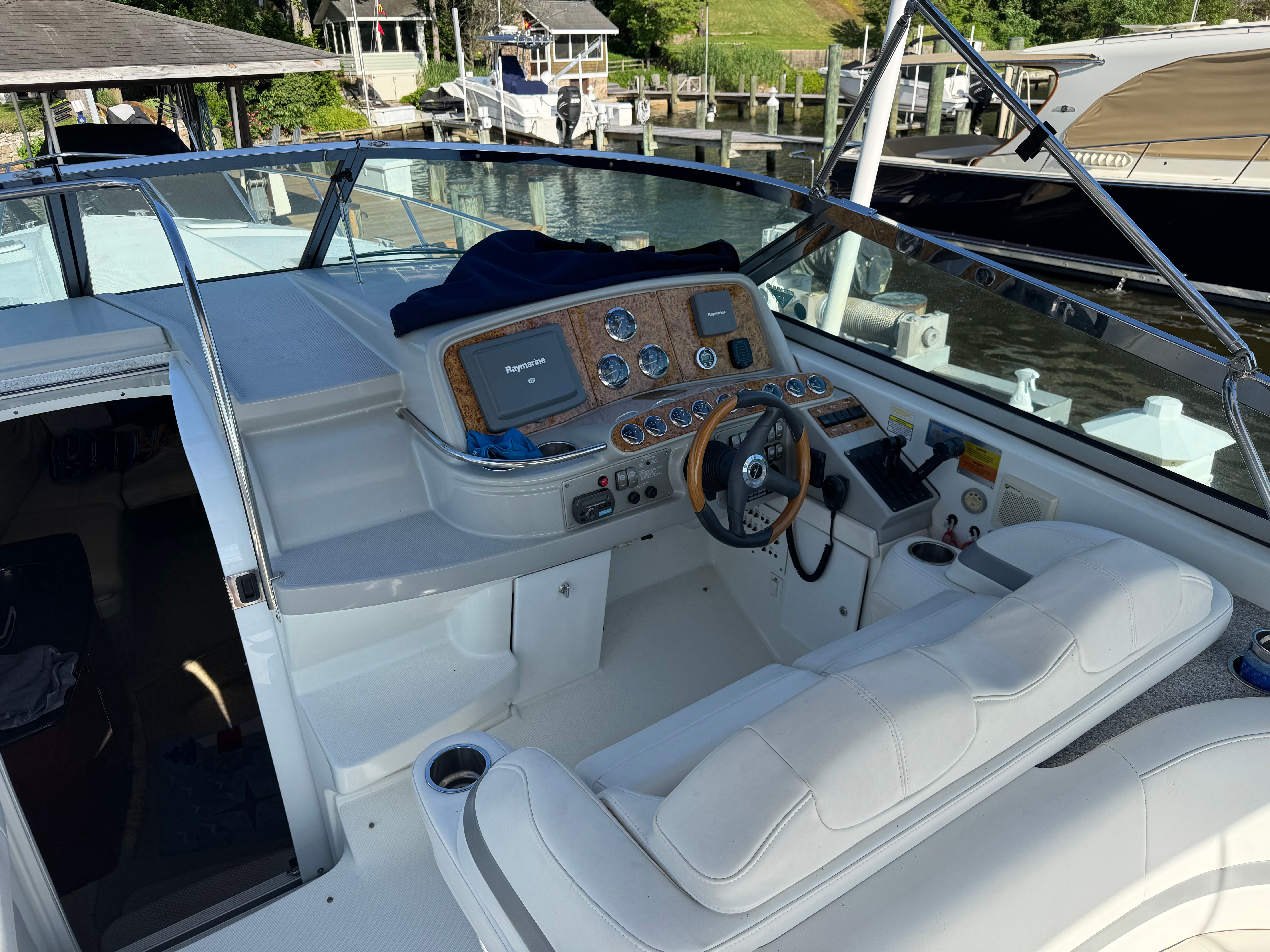 The cockpit of a white boat with a wooden dashboard and steering wheel.